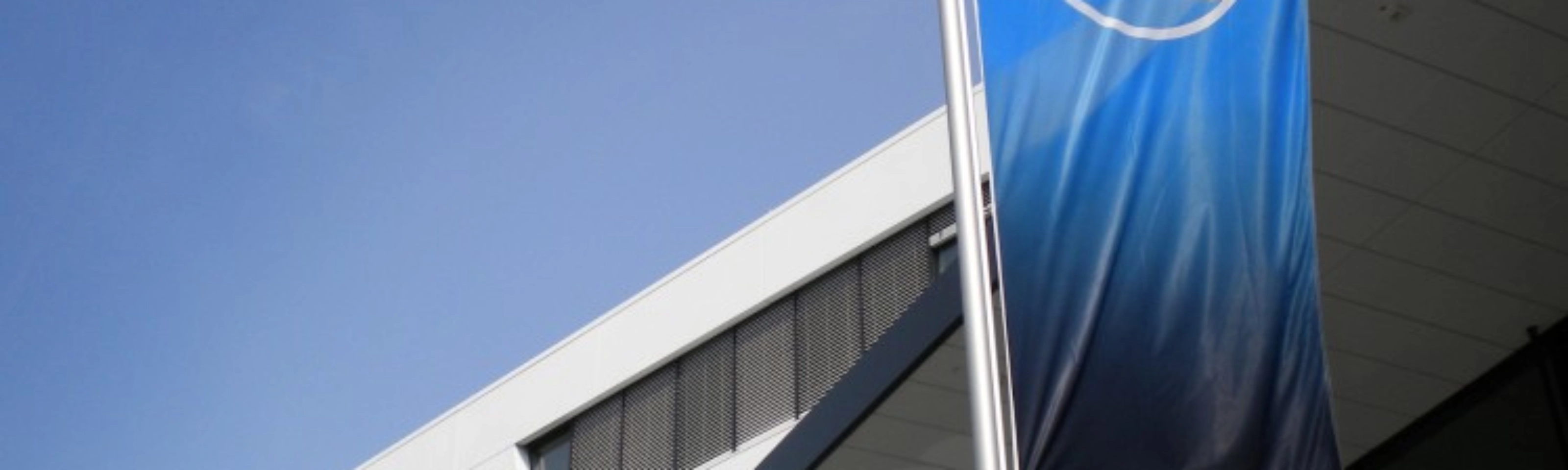 Blaue ZF-Flagge vor einem modernen Bürogebäude mit weißer Fassade.