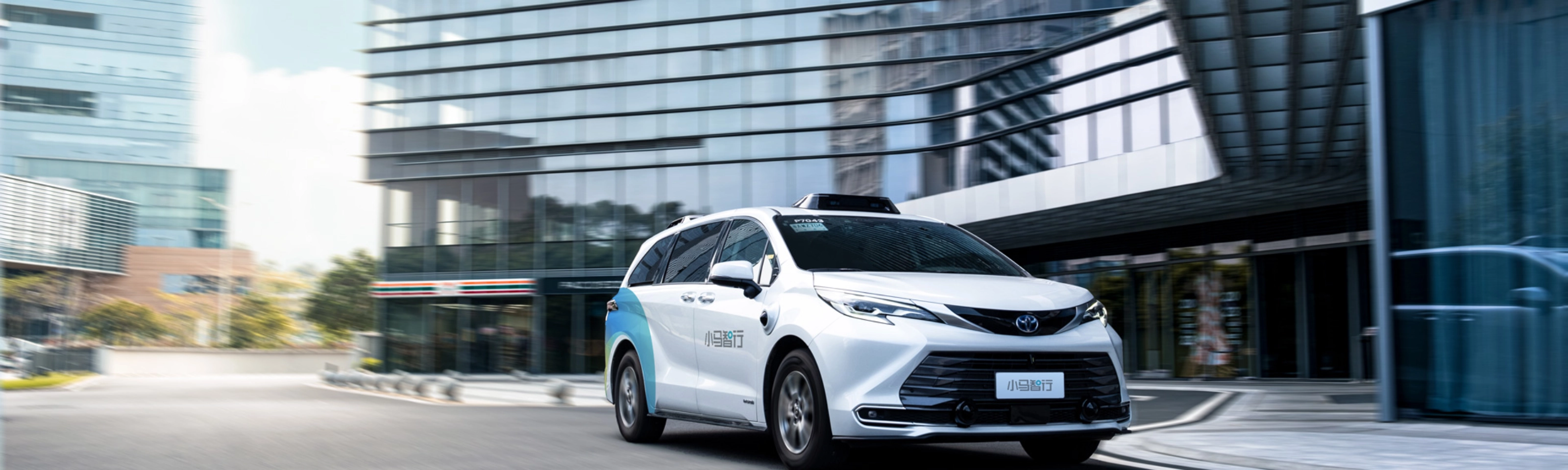 Autonomous minivan driving through modern city street.