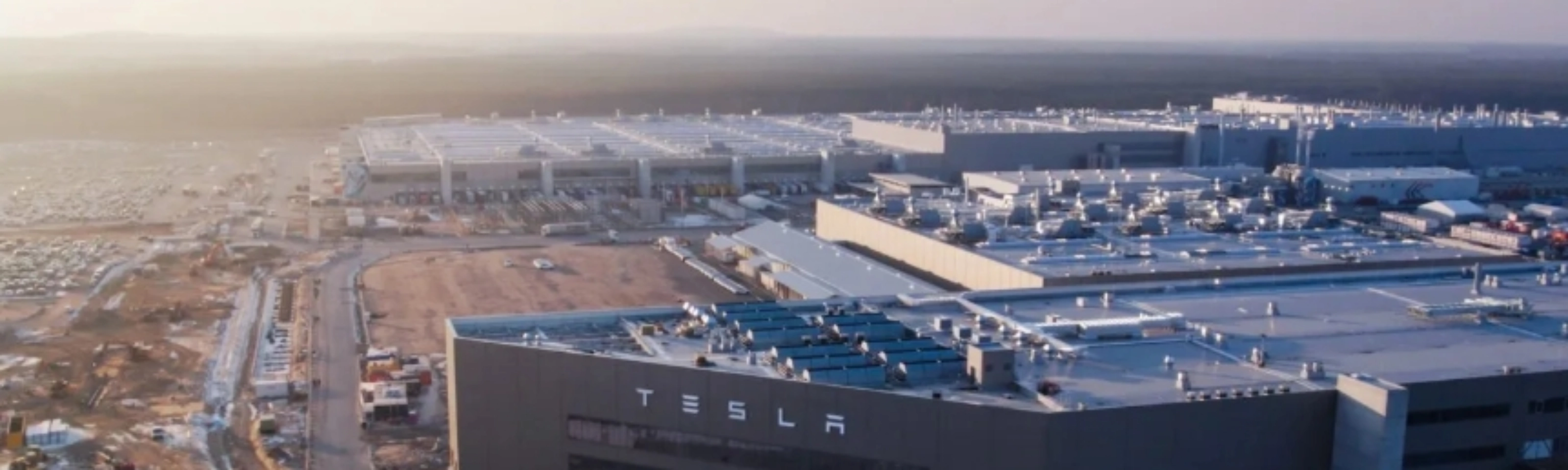 Luftaufnahme eines Tesla-Werks mit großen Produktionsgebäuden.