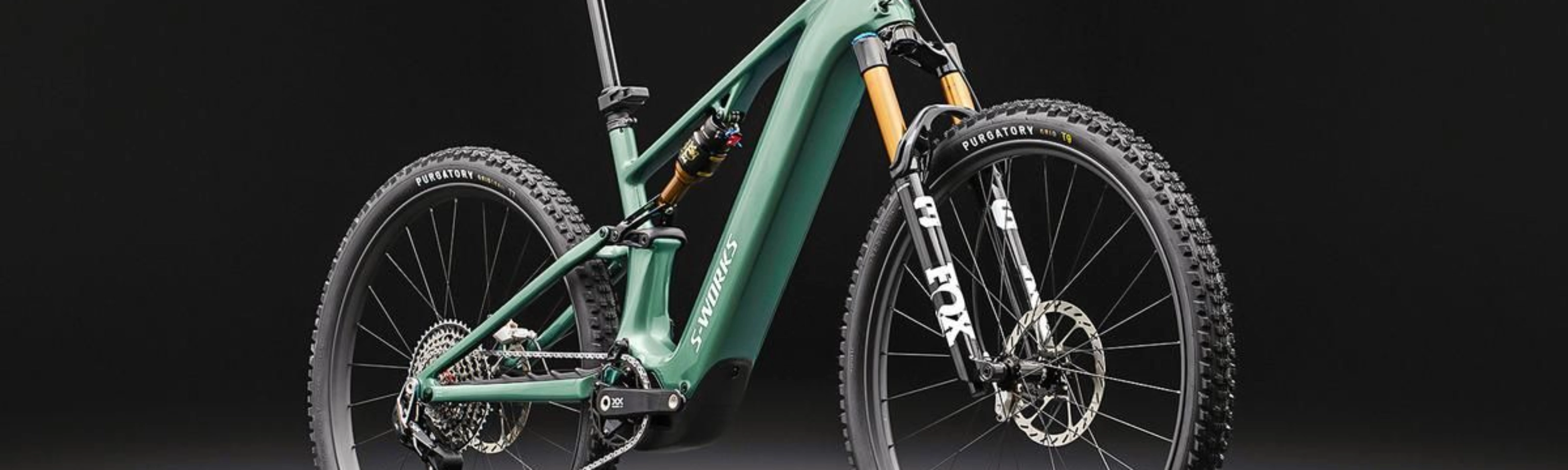 Green full-suspension mountain bike on a dark background.