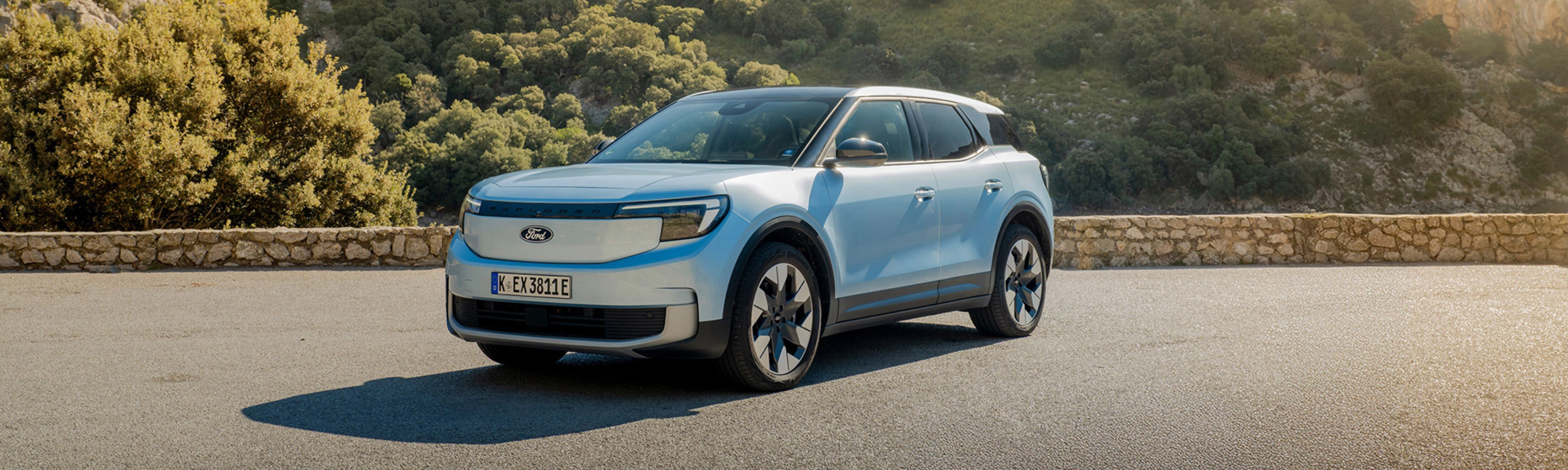Ein hellblaues Elektro-SUV von Ford steht auf einer Bergstraße vor felsiger Hügellandschaft.