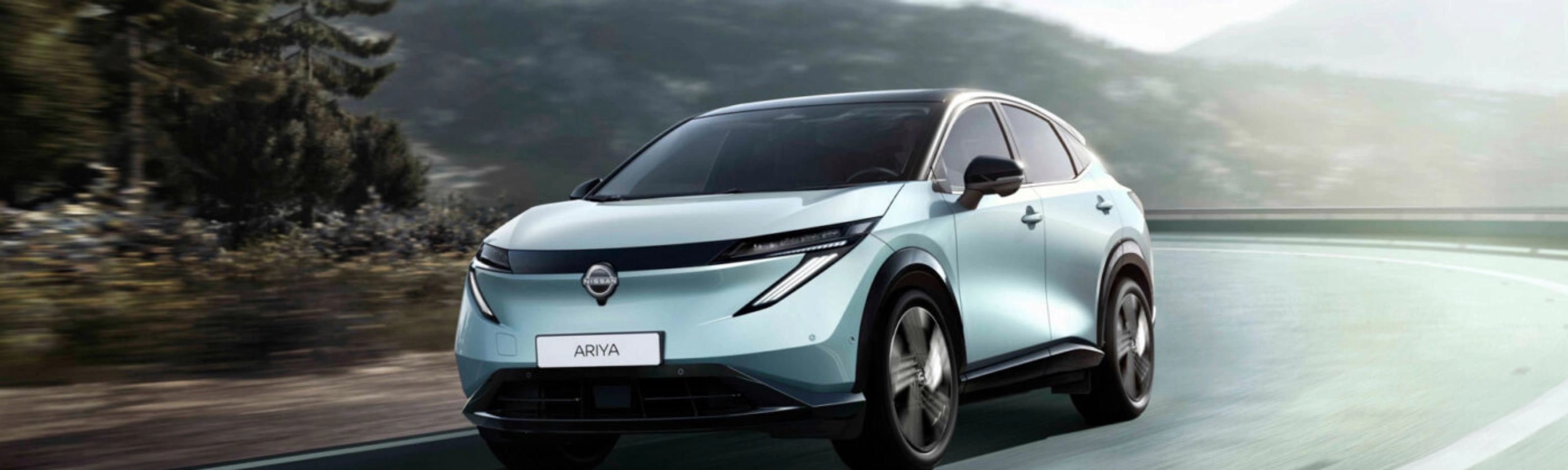 Nissan Ariya electric SUV driving on a mountain road.