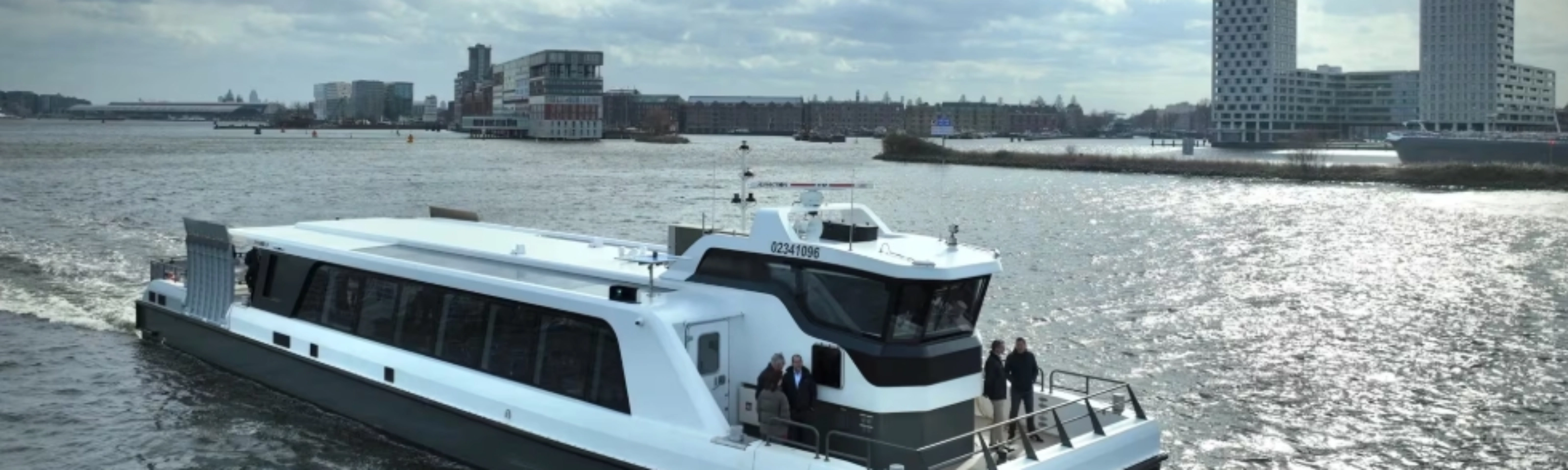 White passenger ferry on a river with modern city buildings in background