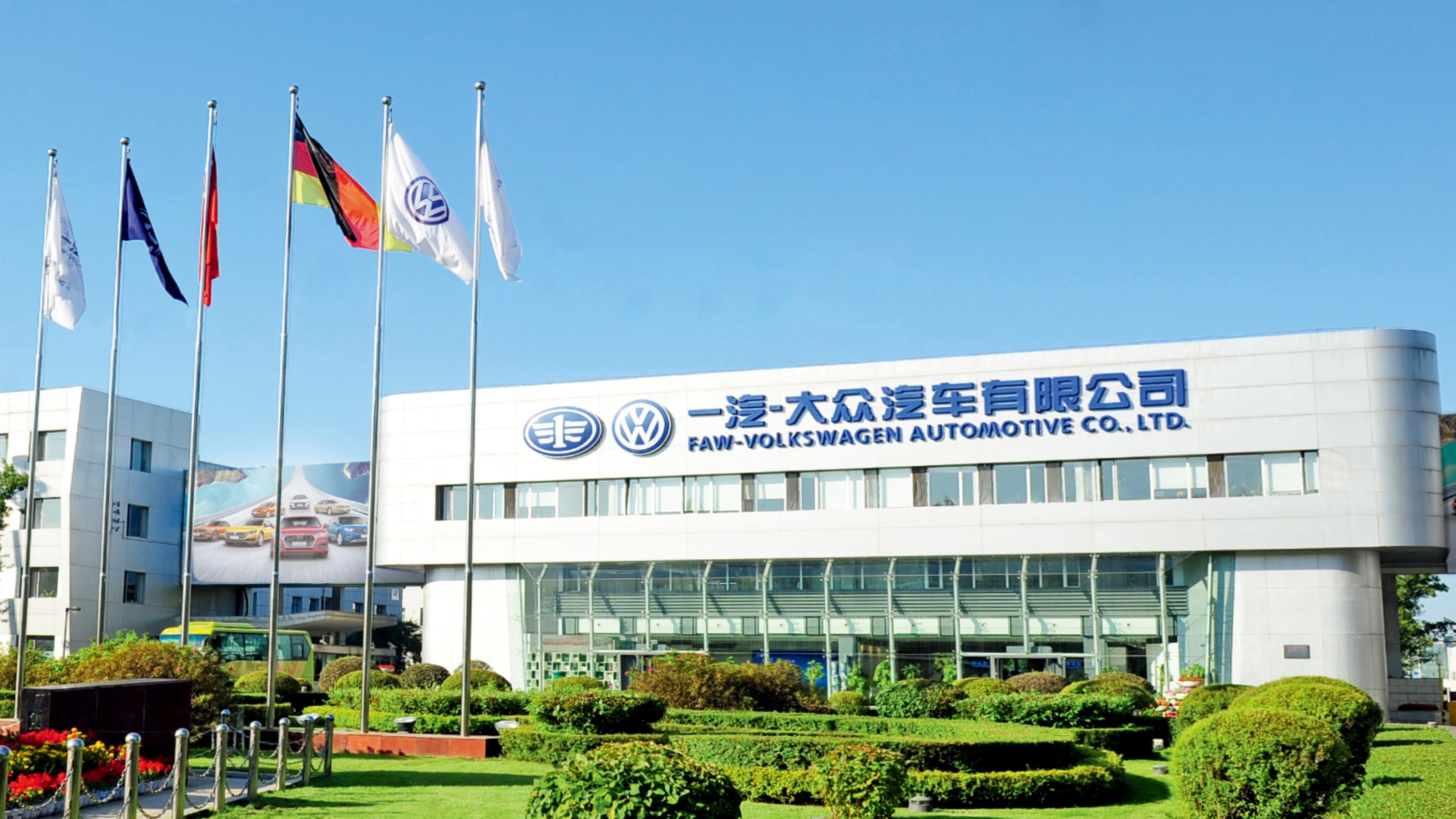 Haupteingang der FAW-Volkswagen Automotive Company mit Fahnen und Firmenschriftzug.