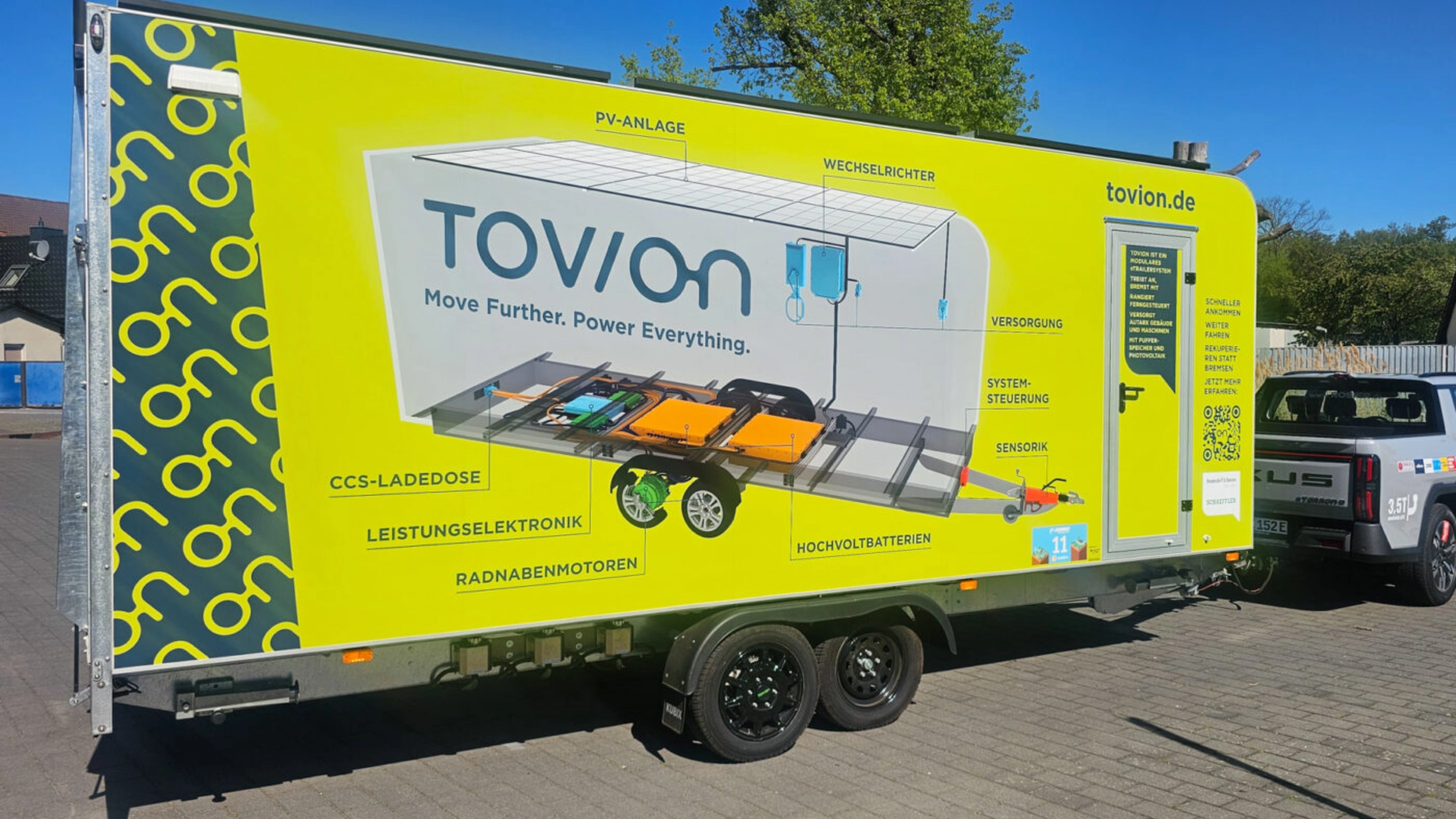 Yellow Tovion trailer with product graphic parked outdoors.