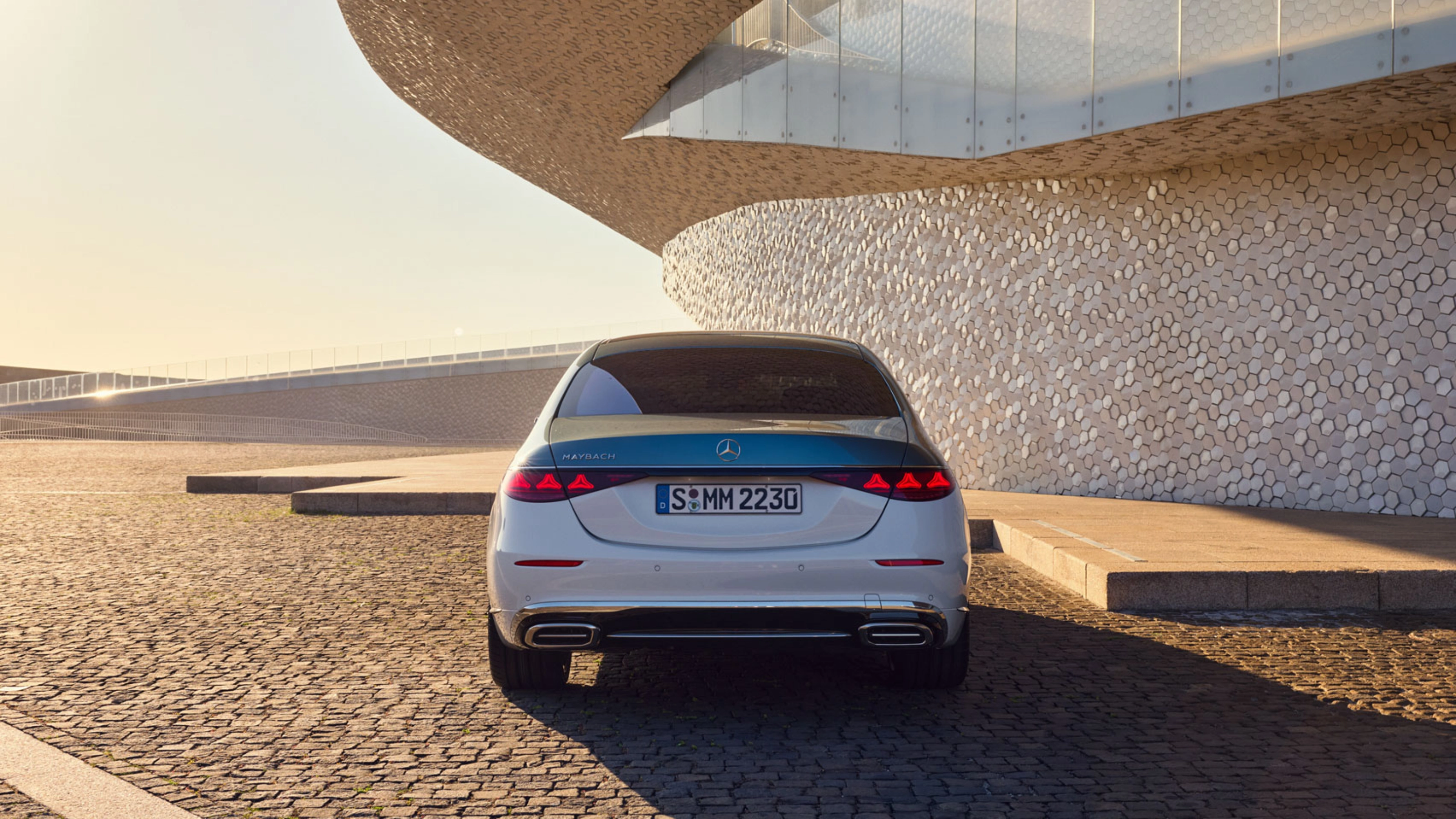 Rückansicht eines weißen Mercedes-Benz vor modernem Gebäude.