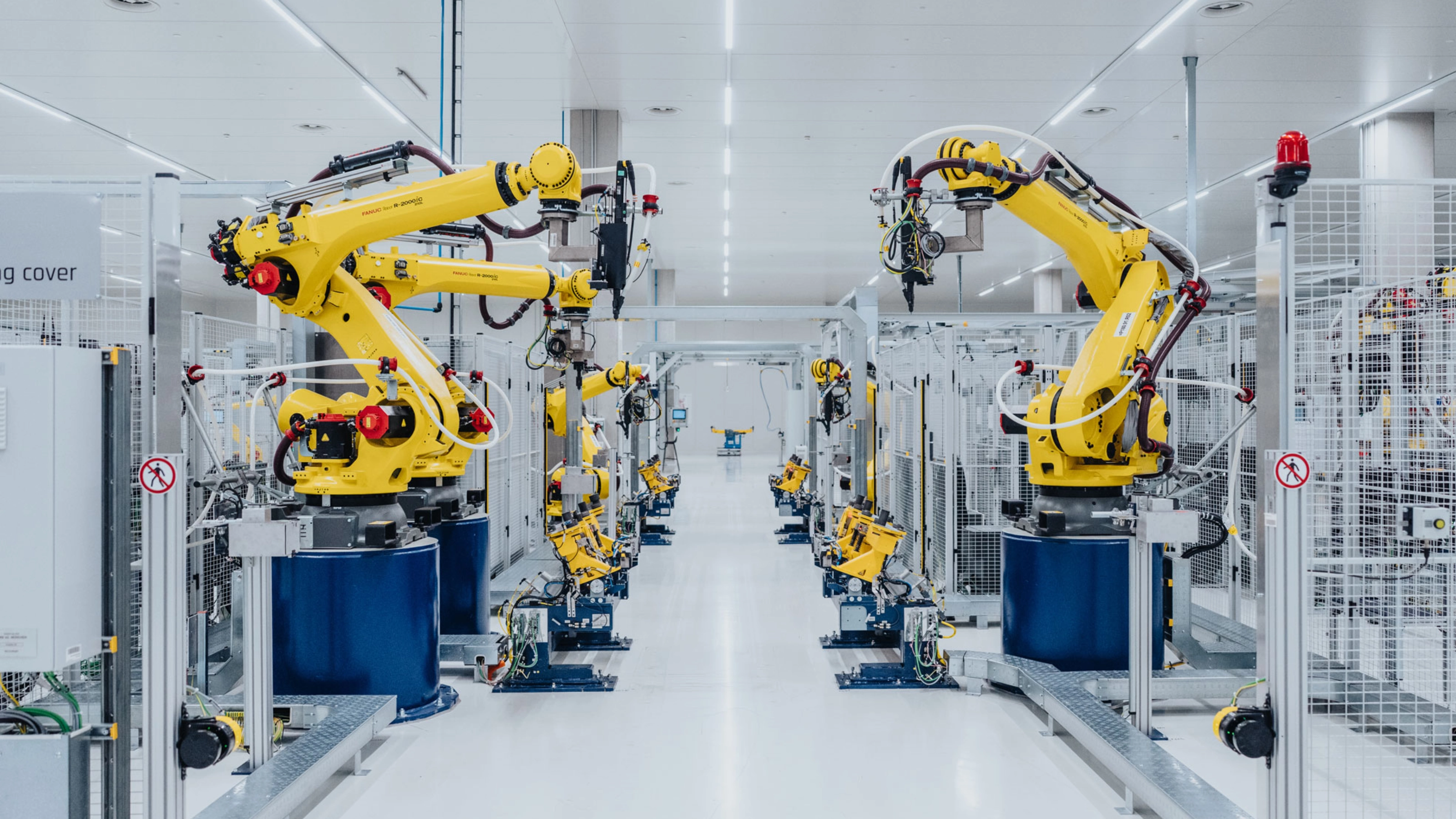 Automatisierte Fertigungslinie mit gelben Industrierobotern in einer Fabrikhalle.