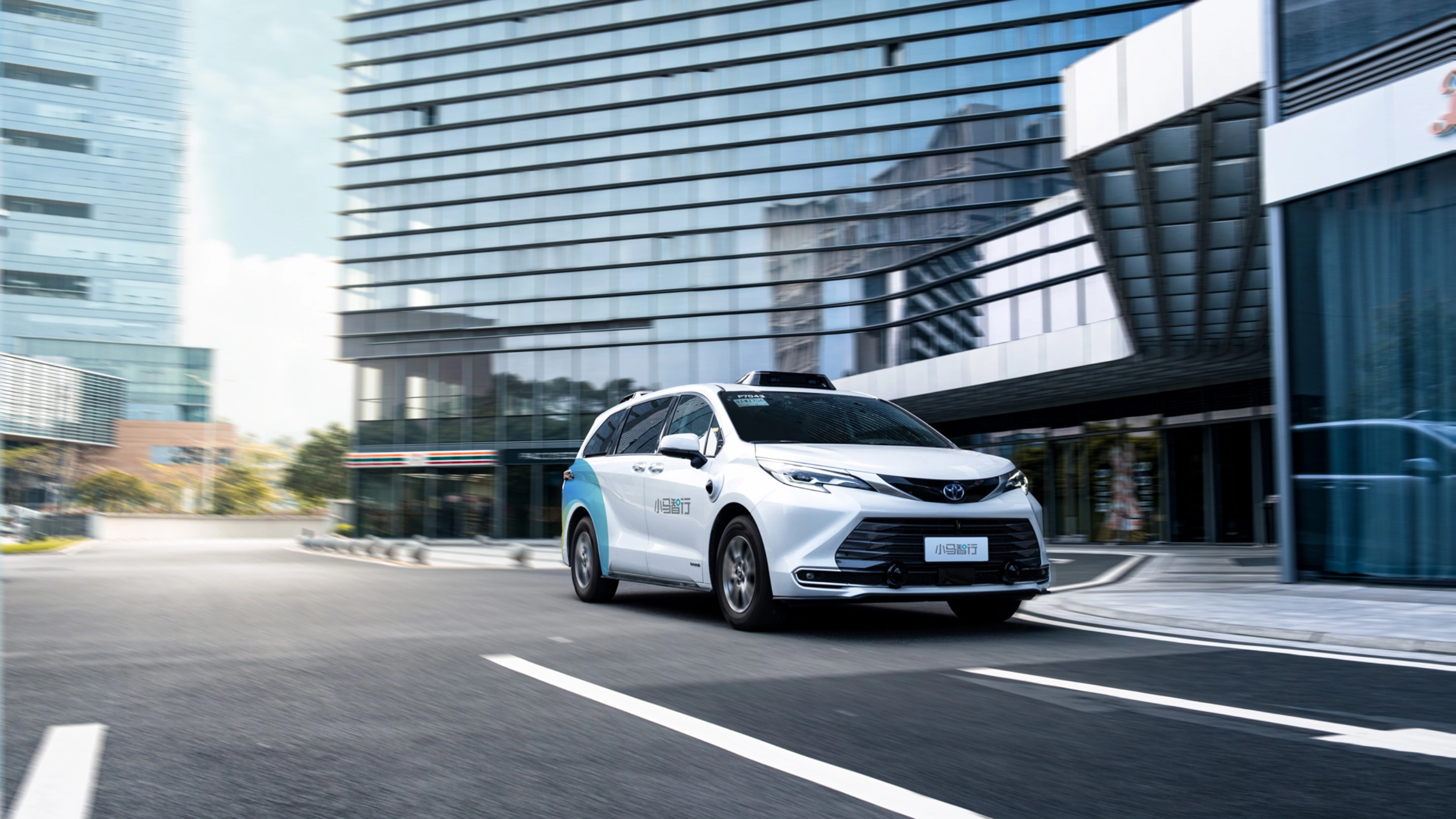Autonomous minivan driving through modern city street.