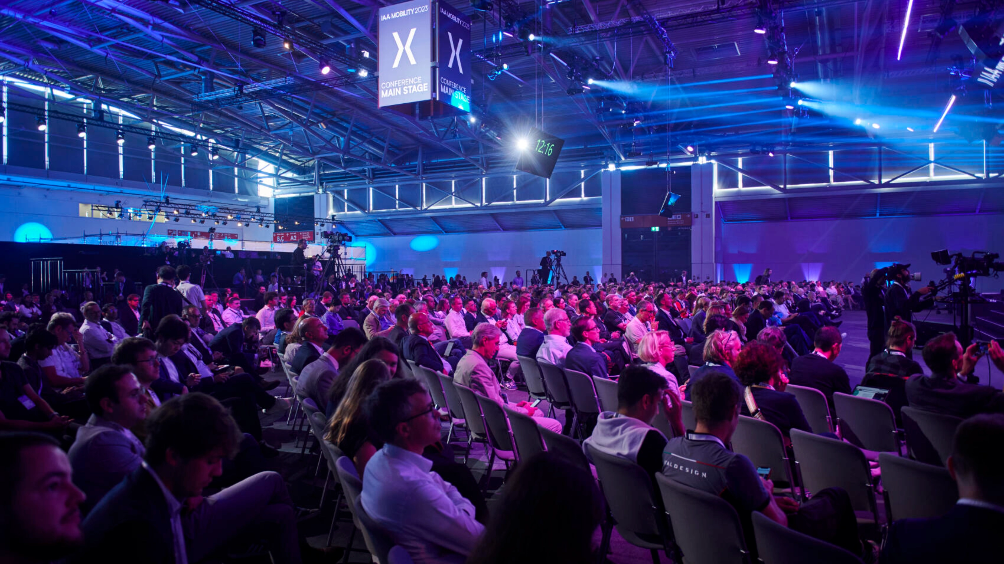 Großes Publikum in einem Konferenzsaal bei der IAA MOBILITY mit Bühnenlicht und Kameras.