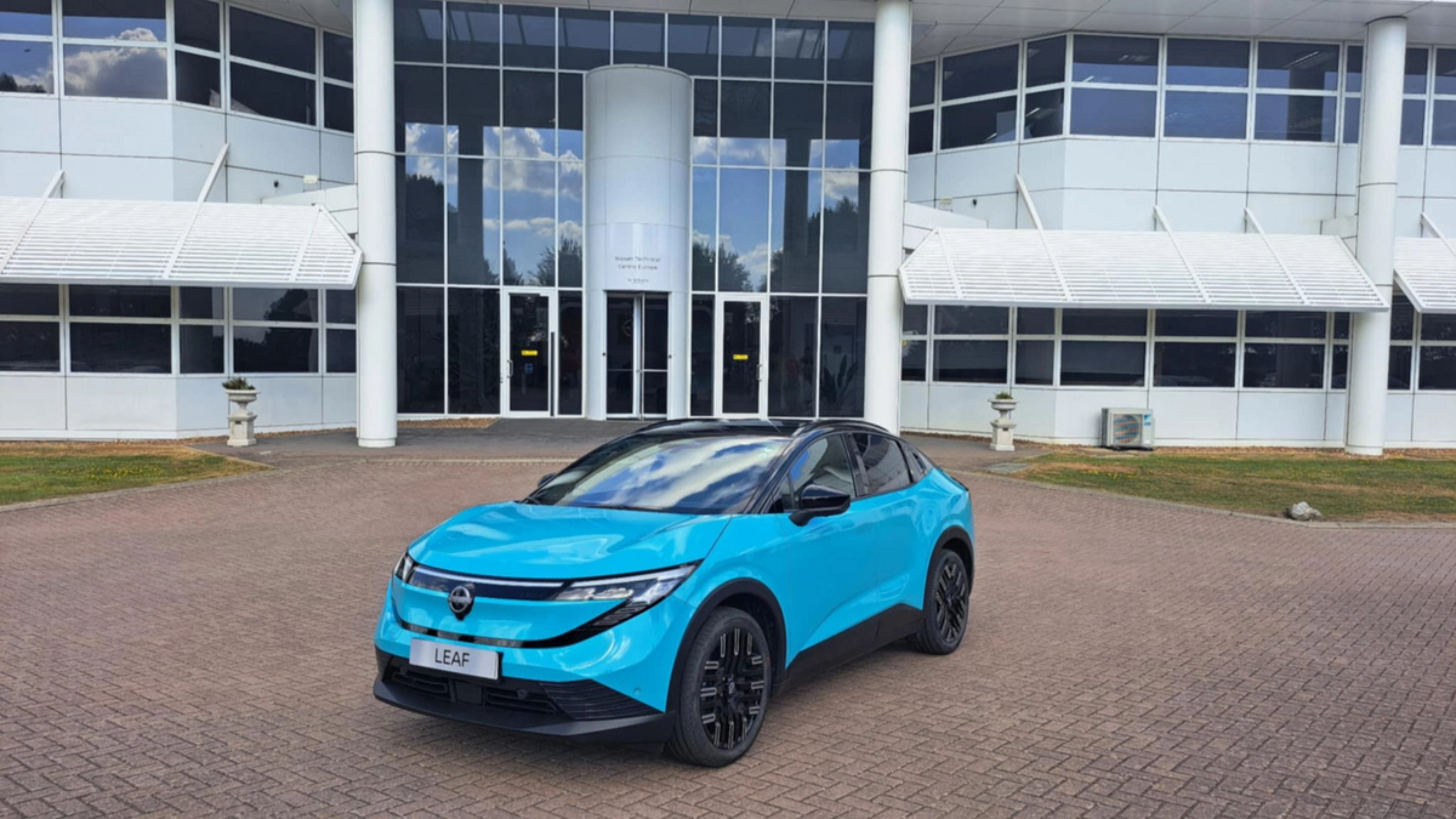 Blauer Nissan Crossover steht vor einem modernen Gebäude mit Glasfassade.