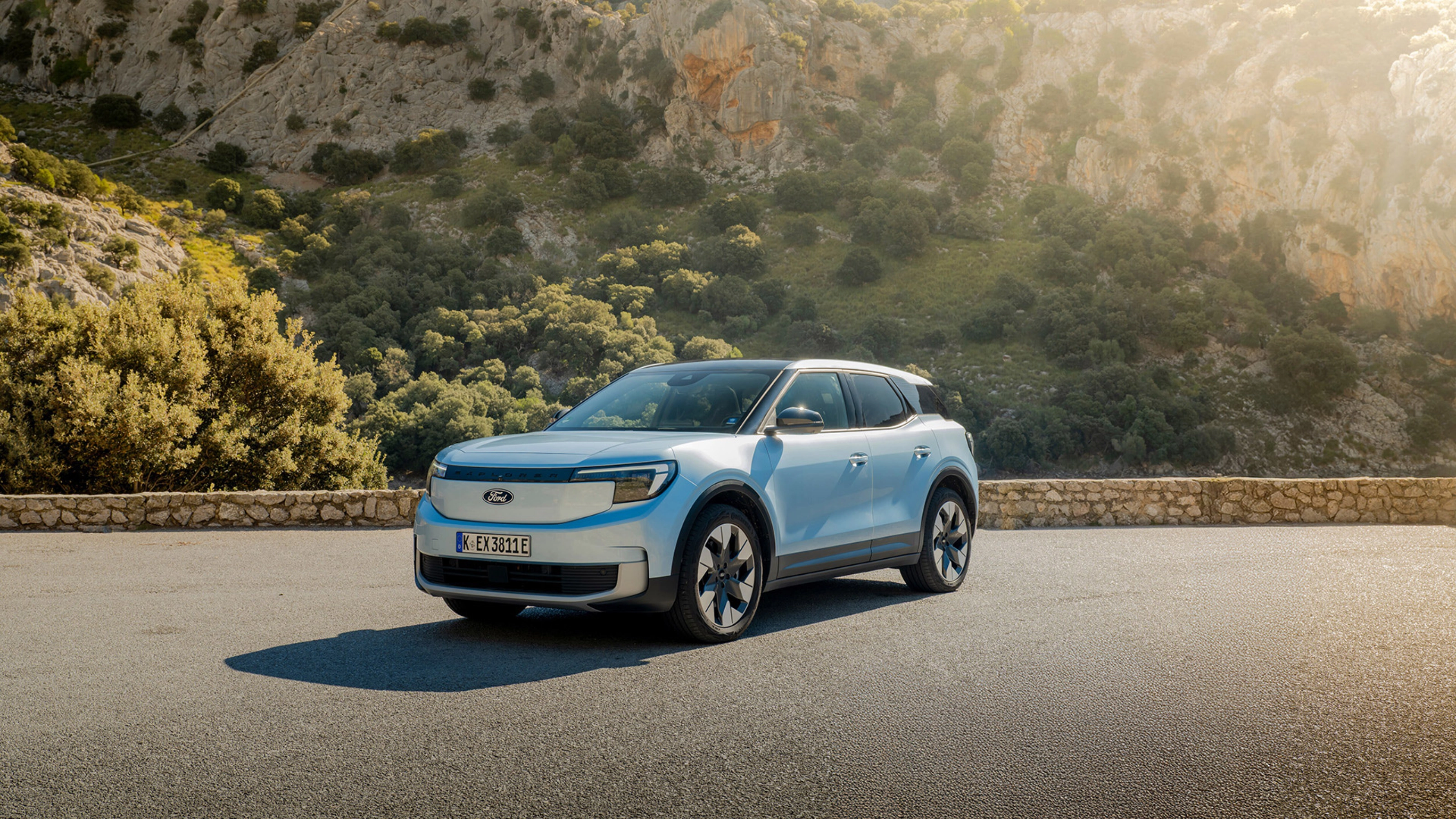Ein hellblaues Elektro-SUV von Ford steht auf einer Bergstraße vor felsiger Hügellandschaft.