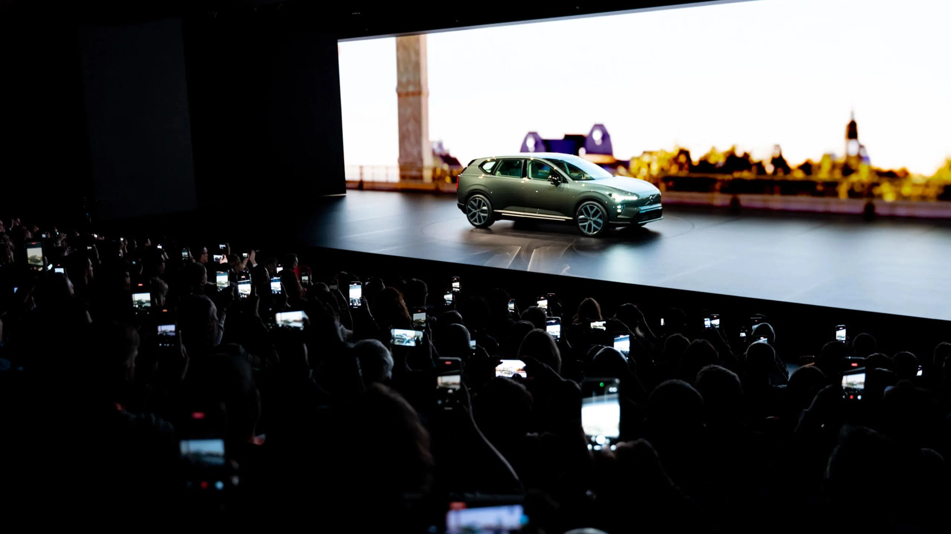 Elektrischer SUV wird auf einer Bühne präsentiert, das Publikum fotografiert mit Smartphones.