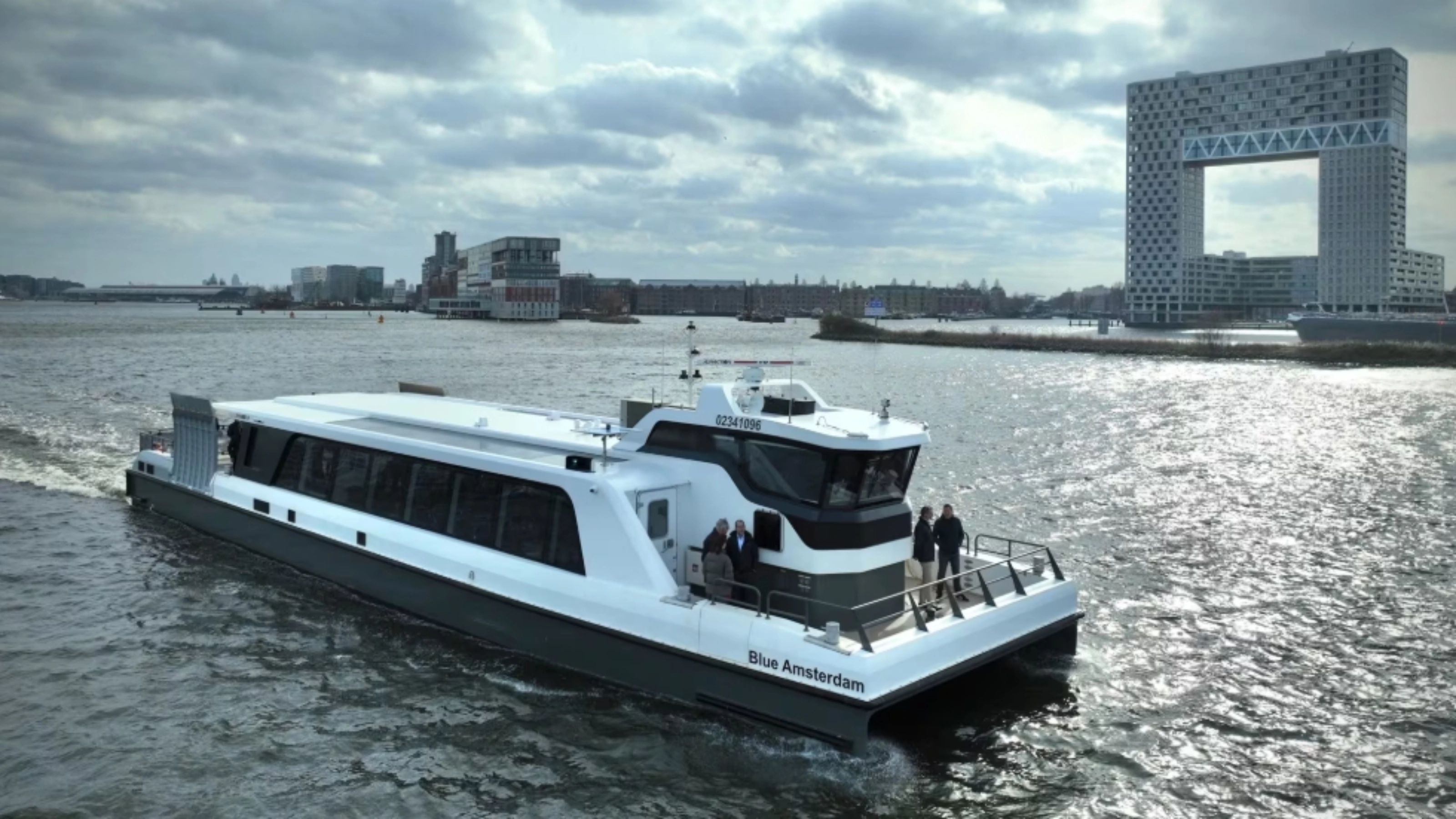 White passenger ferry on a river with modern city buildings in background