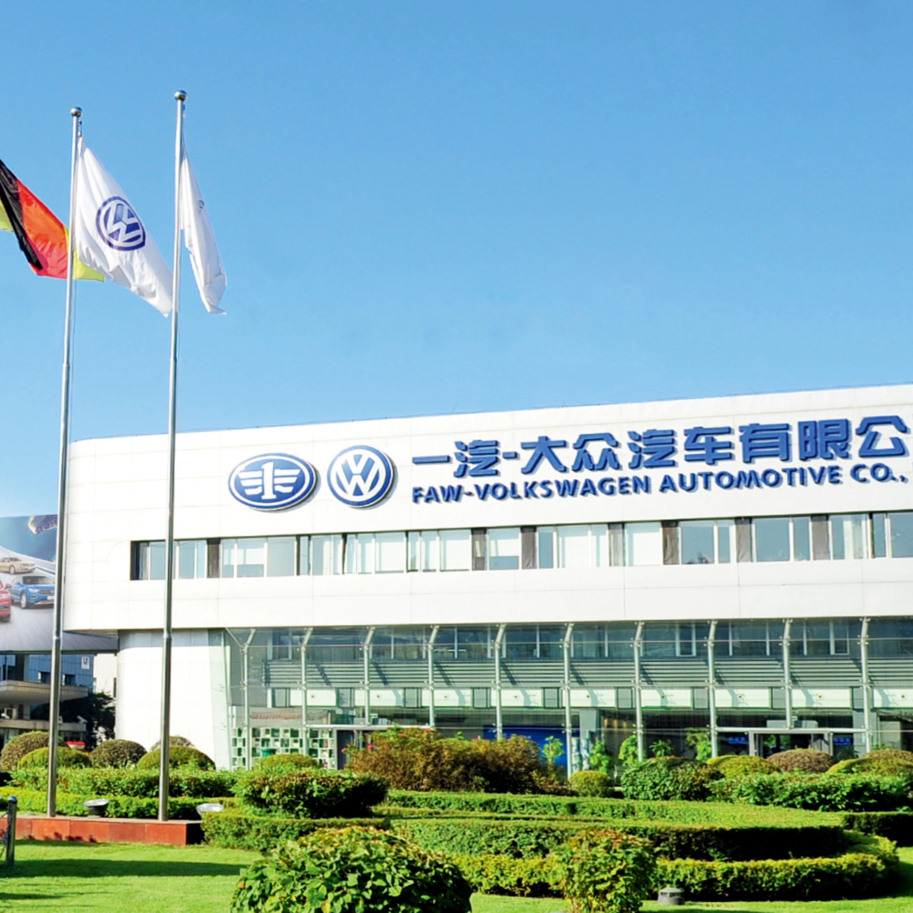 Haupteingang der FAW-Volkswagen Automotive Company mit Fahnen und Firmenschriftzug.