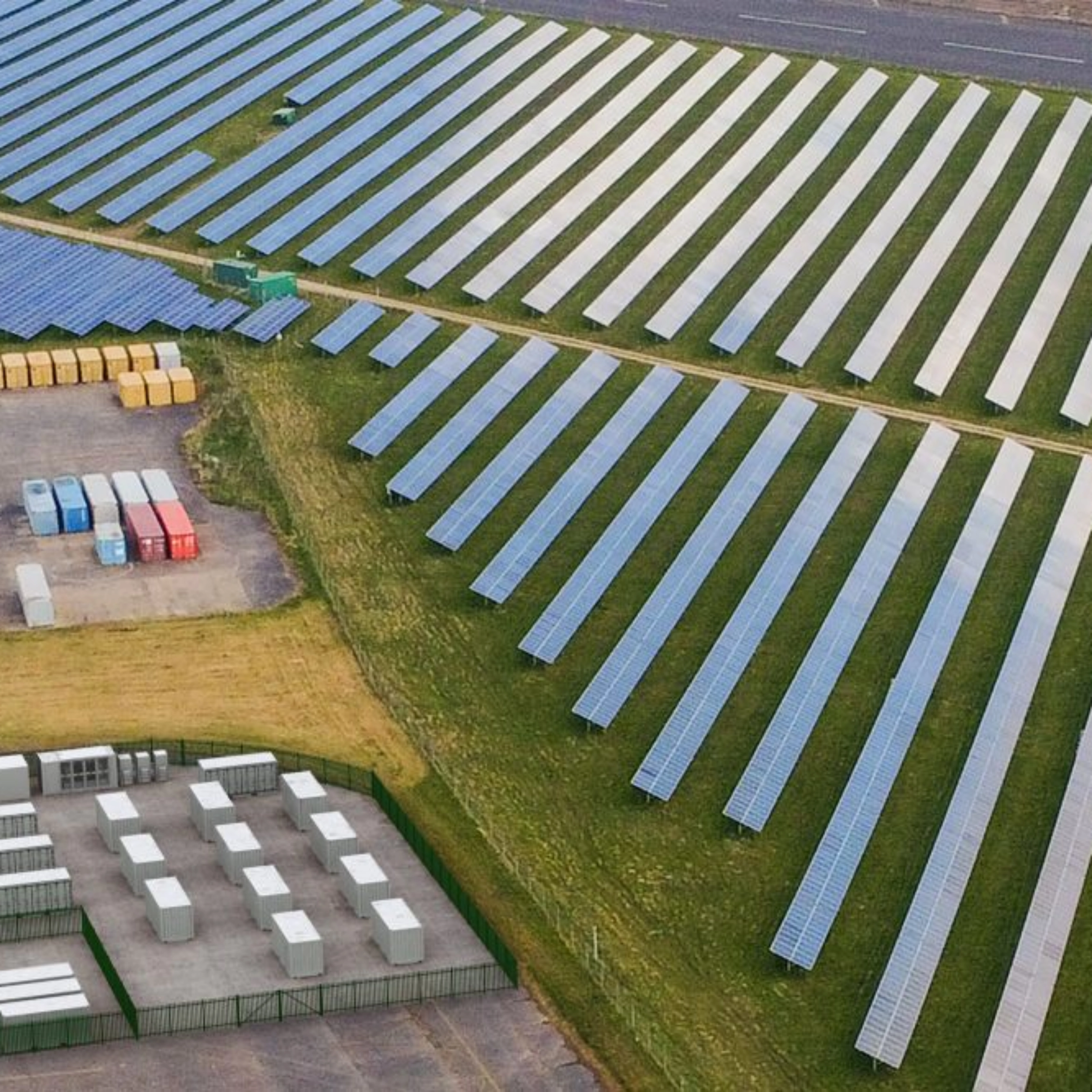 Luftaufnahme einer Solaranlage mit Reihen von Solarpaneelen und mehreren Containern.