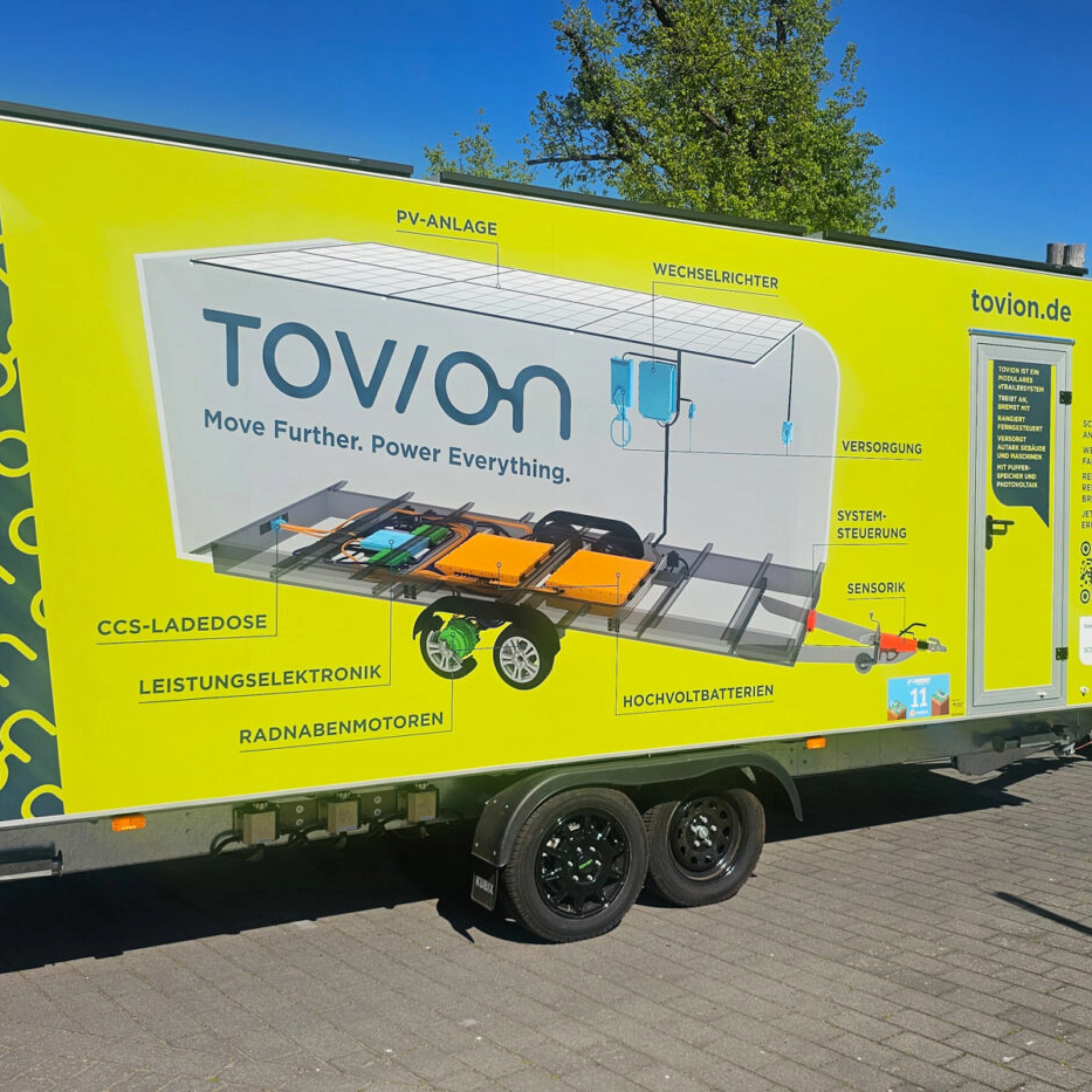 Yellow Tovion trailer with product graphic parked outdoors.