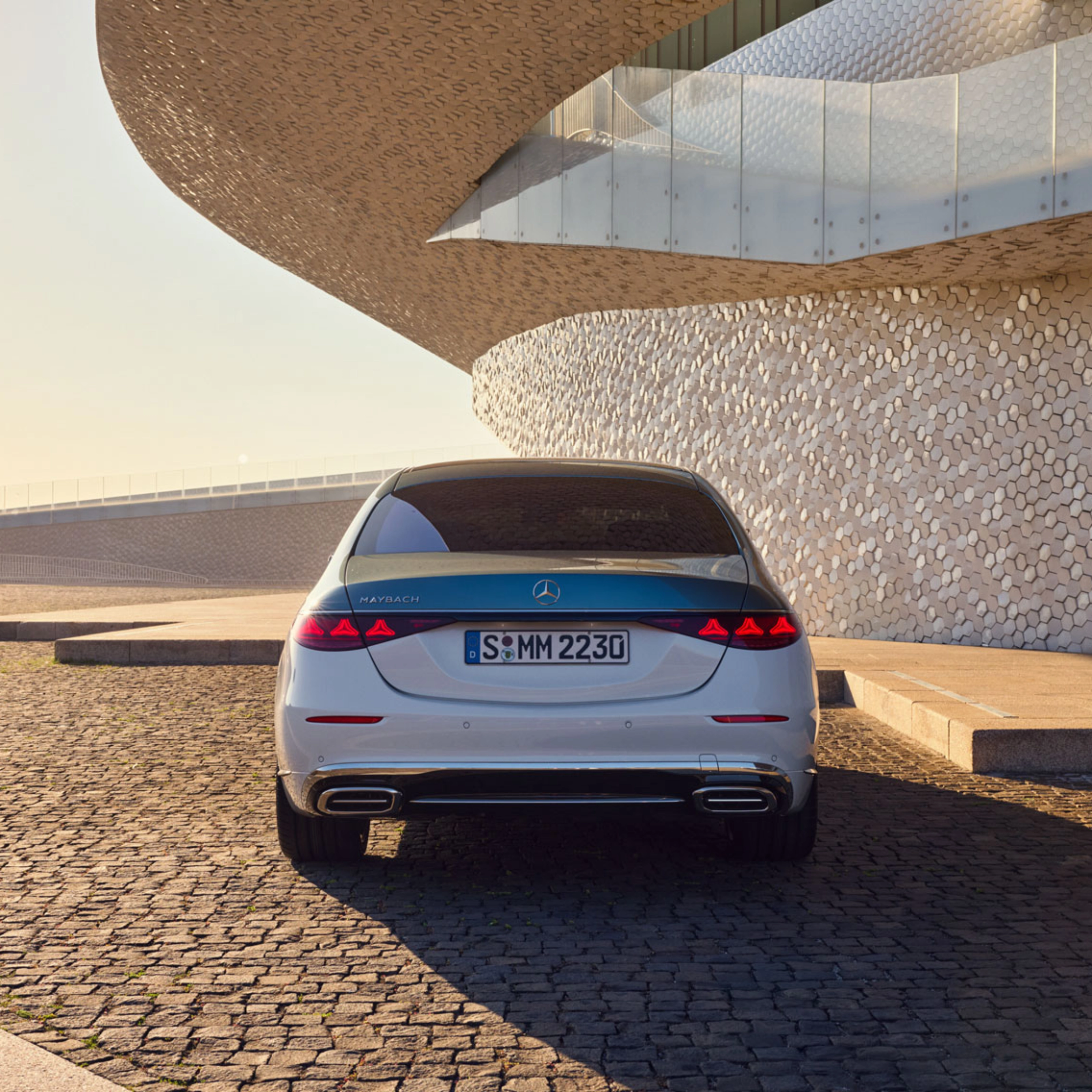 Rückansicht eines weißen Mercedes-Benz vor modernem Gebäude.