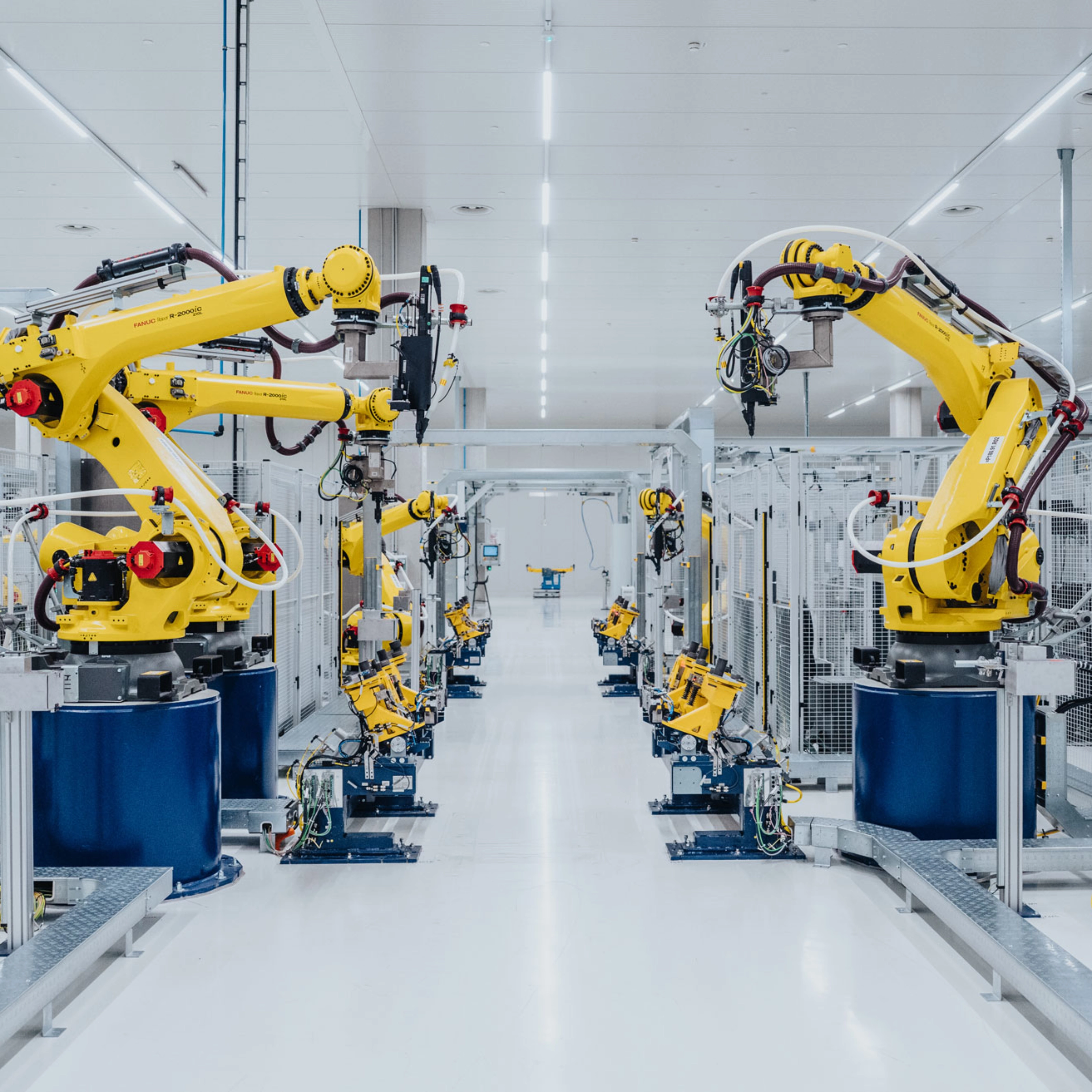 Automatisierte Fertigungslinie mit gelben Industrierobotern in einer Fabrikhalle.