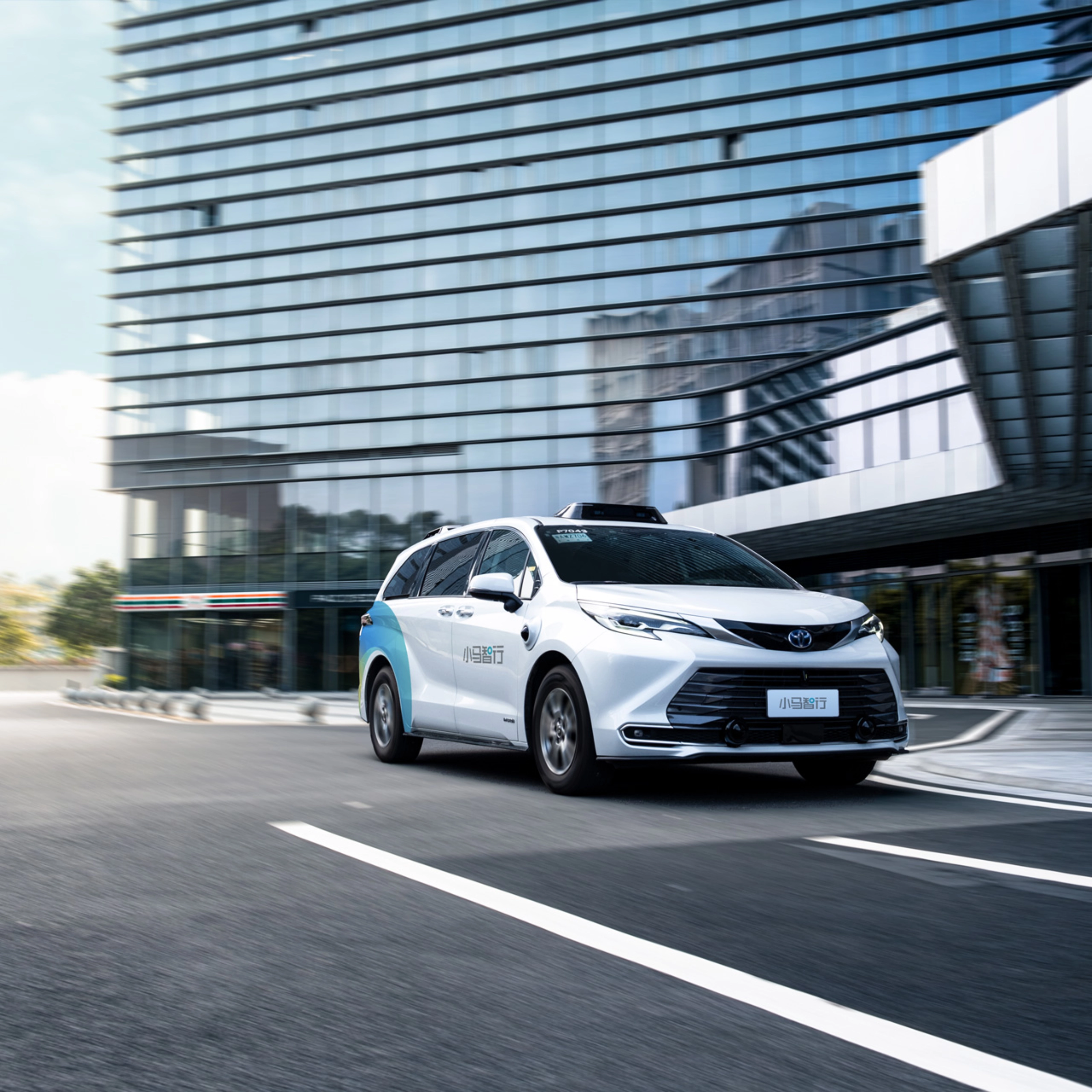 Autonomous minivan driving through modern city street.