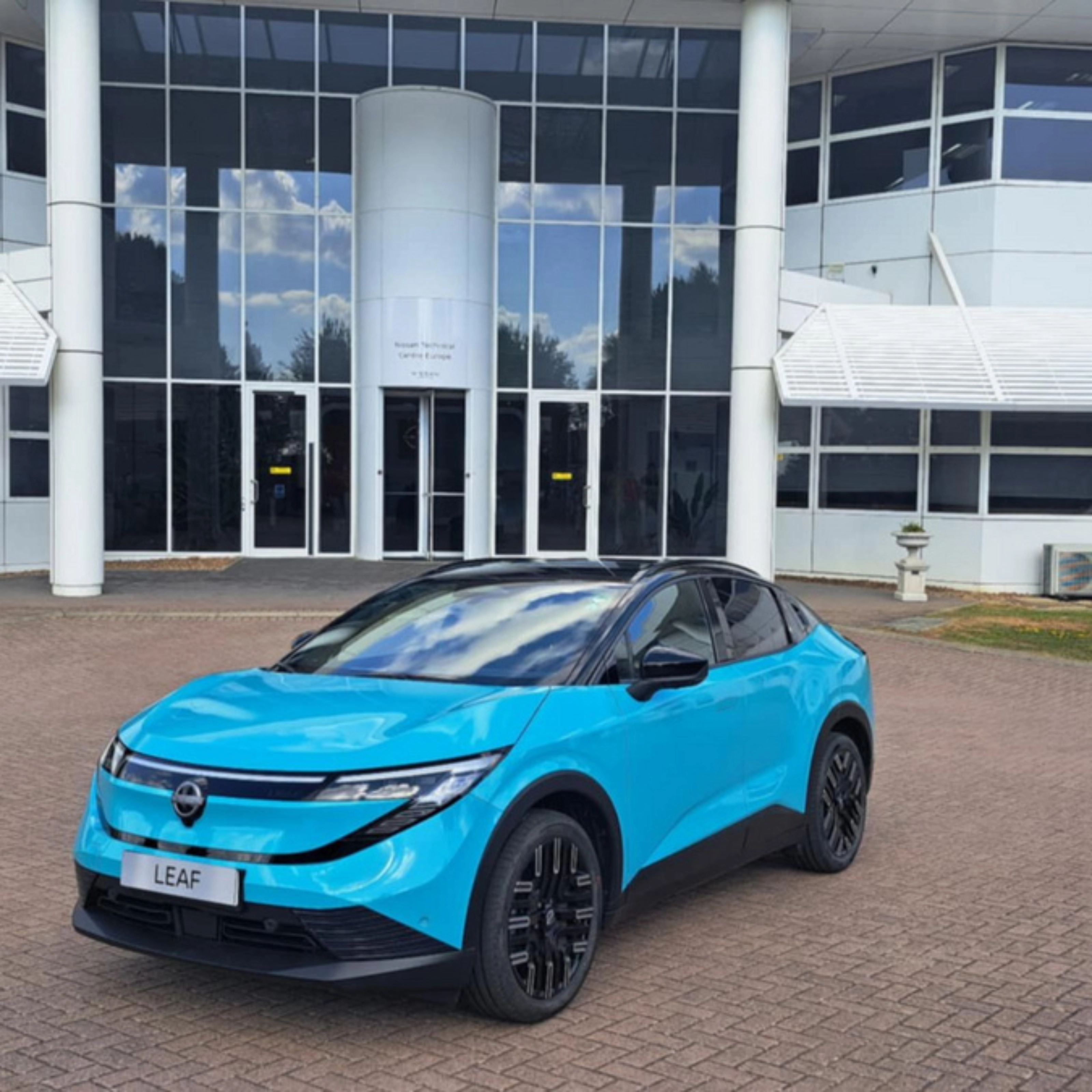Blauer Nissan Crossover steht vor einem modernen Gebäude mit Glasfassade.