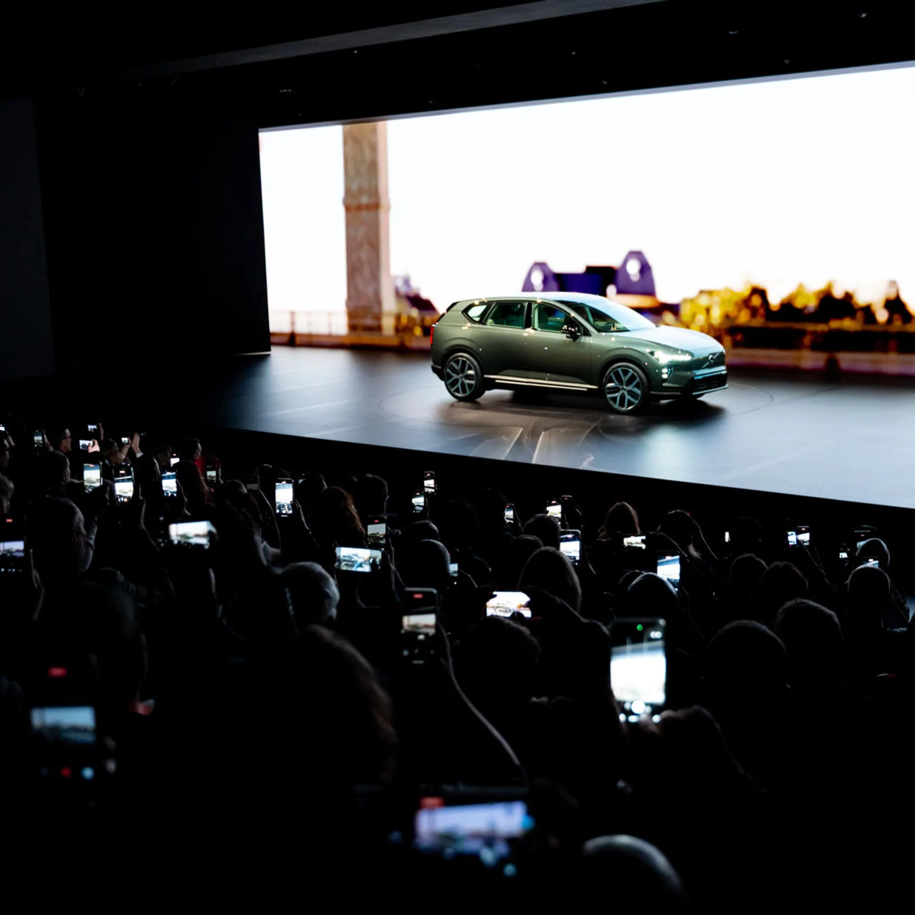 Elektrischer SUV wird auf einer Bühne präsentiert, das Publikum fotografiert mit Smartphones.