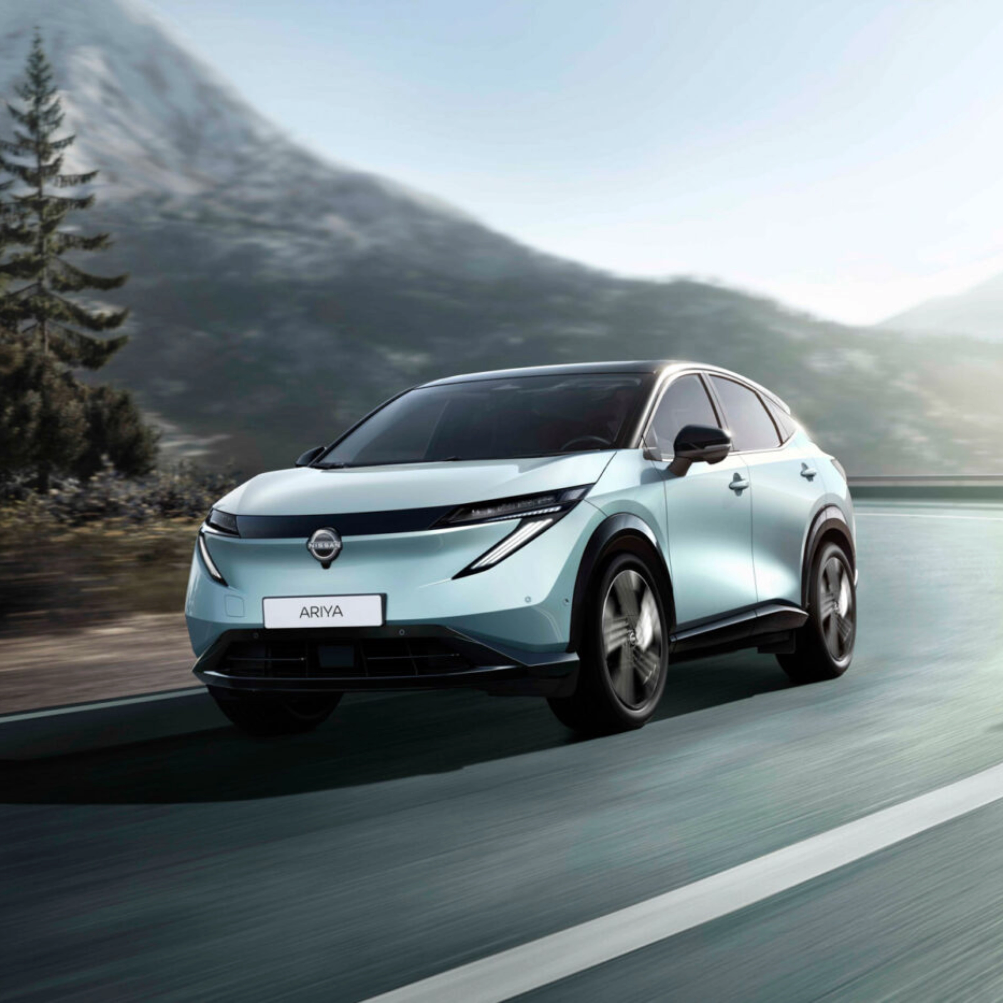 Nissan Ariya electric SUV driving on a mountain road.