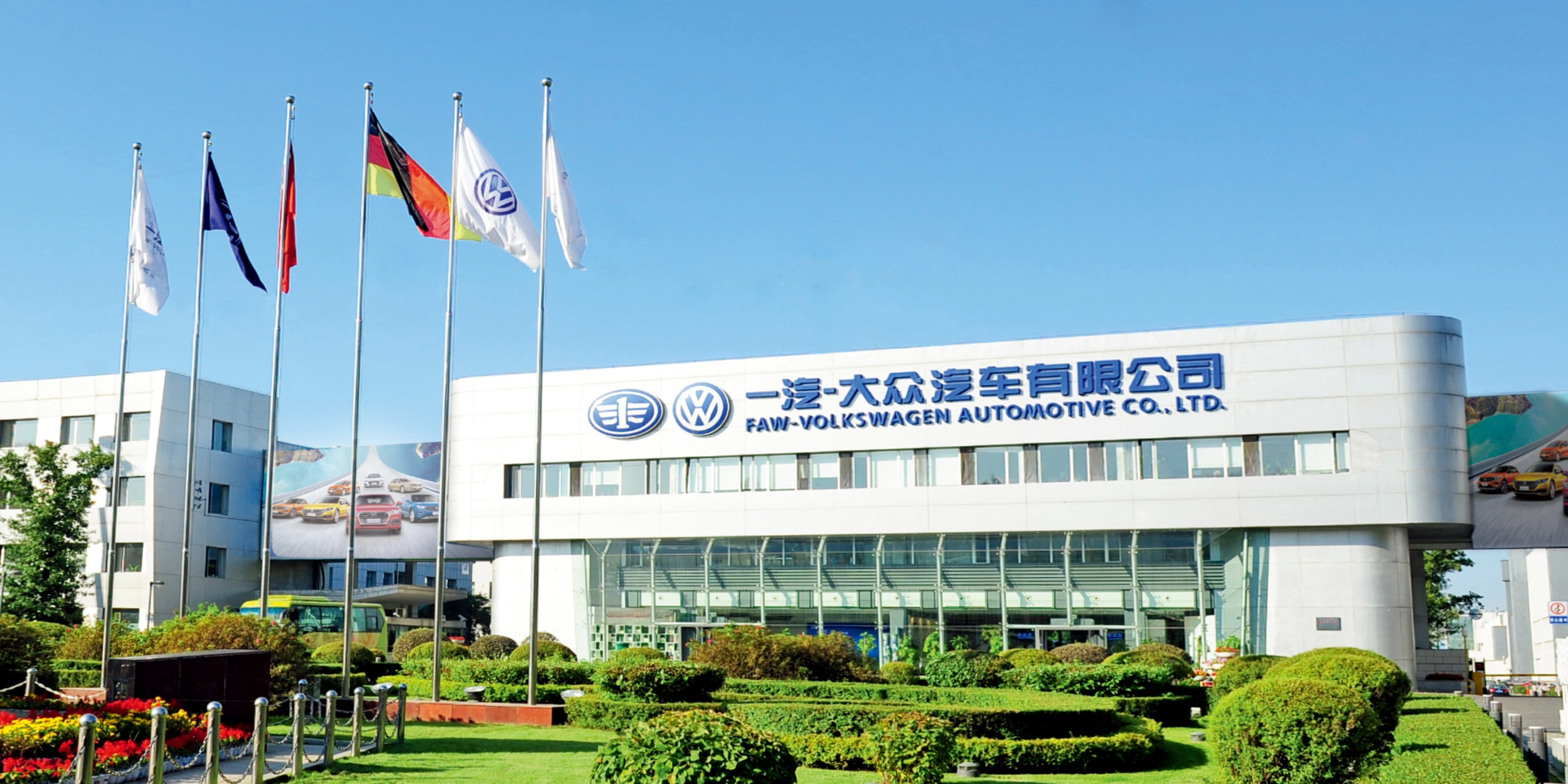 Haupteingang der FAW-Volkswagen Automotive Company mit Fahnen und Firmenschriftzug.