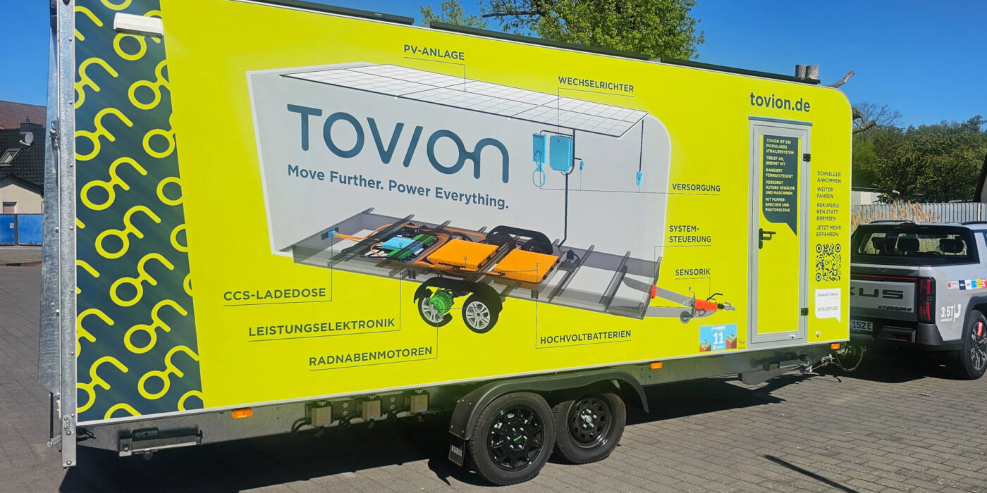 Yellow Tovion trailer with product graphic parked outdoors.