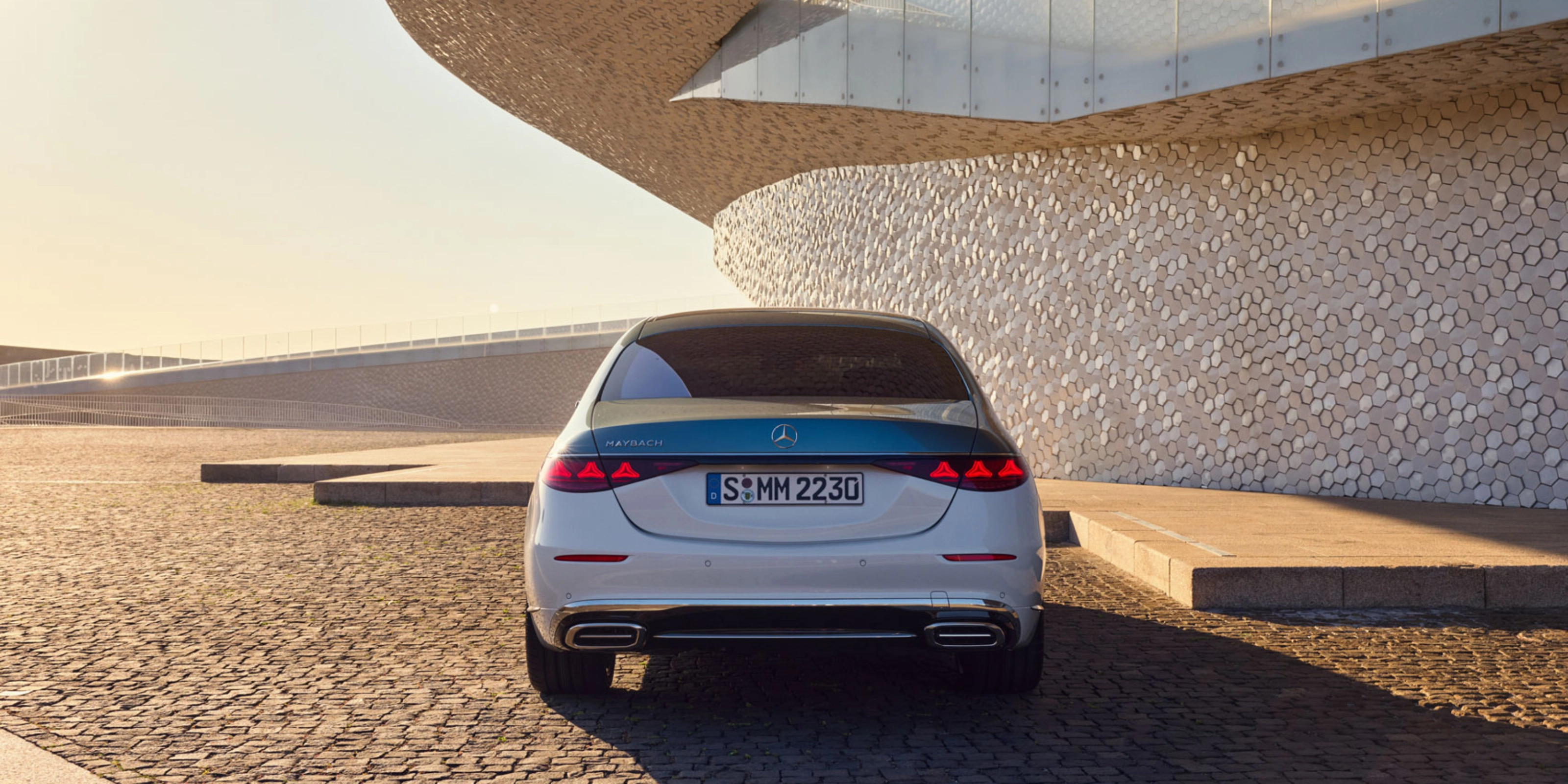 Rückansicht eines weißen Mercedes-Benz vor modernem Gebäude.