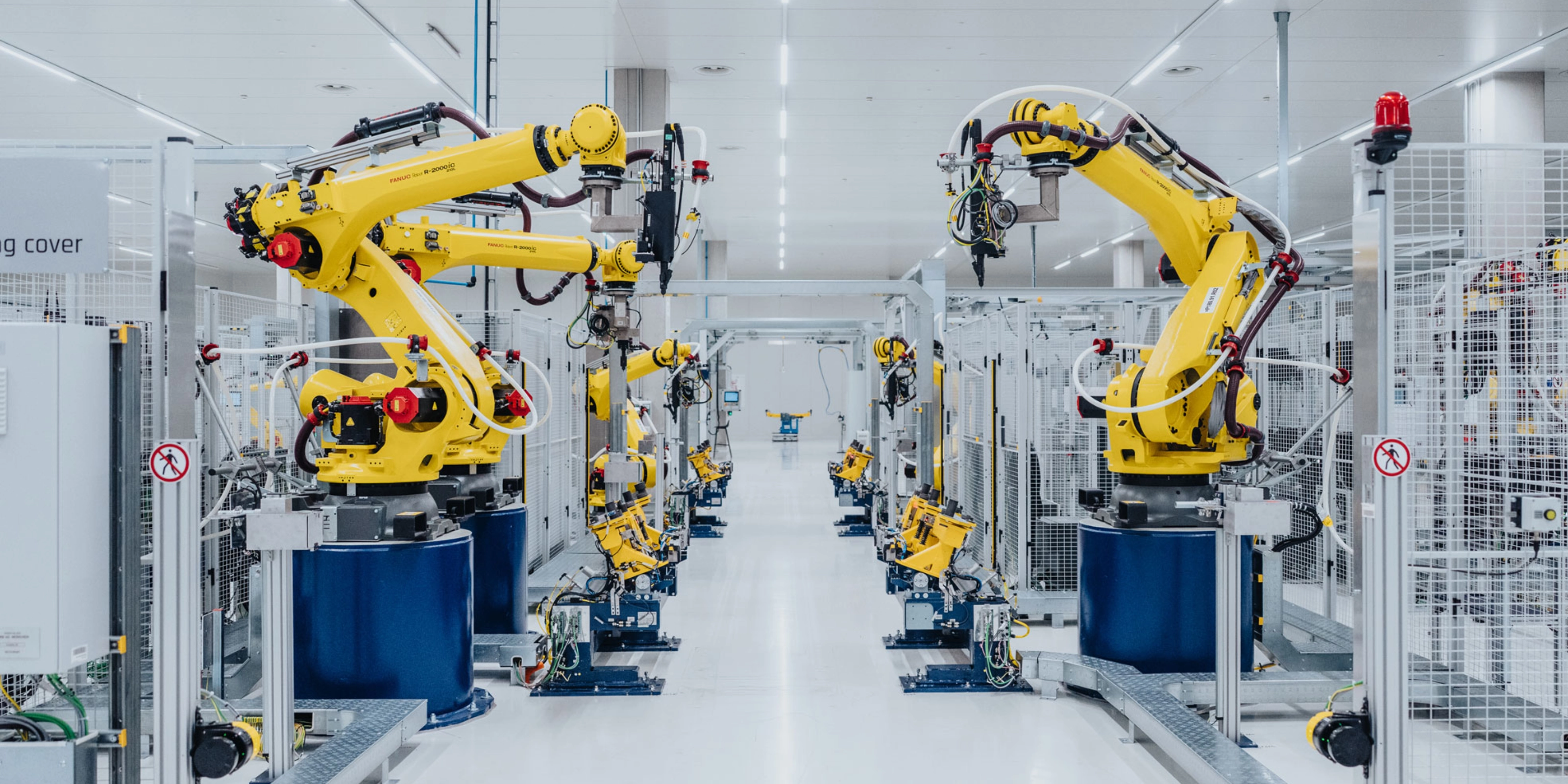 Automatisierte Fertigungslinie mit gelben Industrierobotern in einer Fabrikhalle.