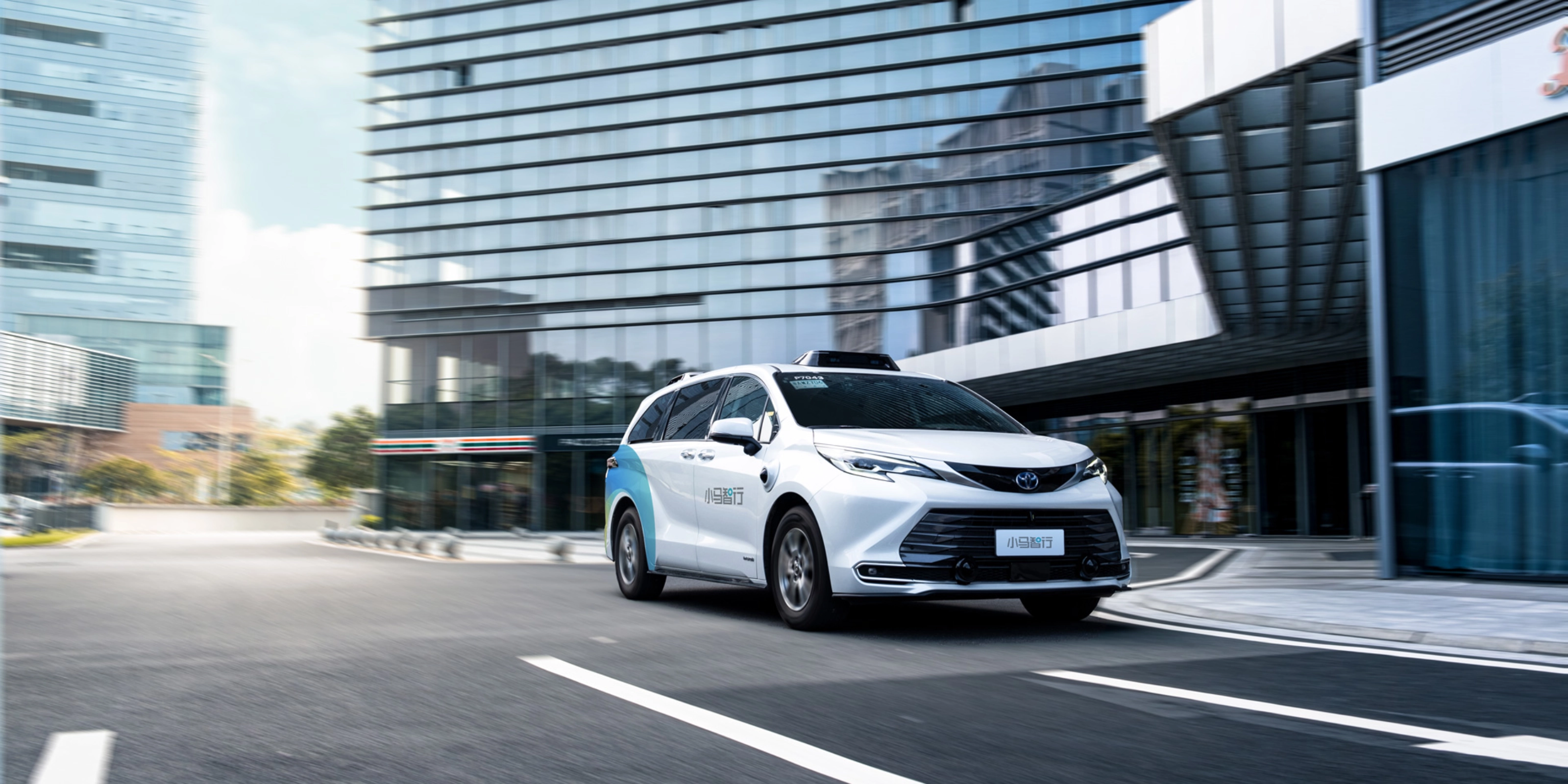 Autonomous minivan driving through modern city street.