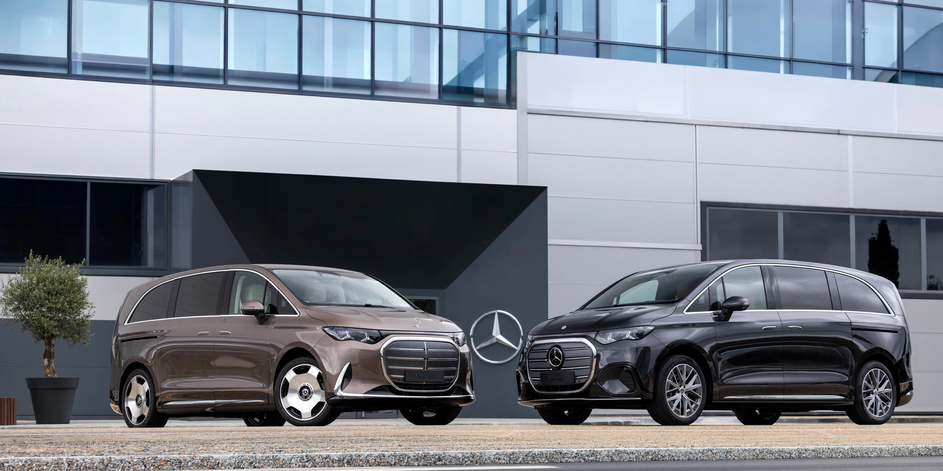 Two Mercedes-Benz vans parked in front of a modern office building.