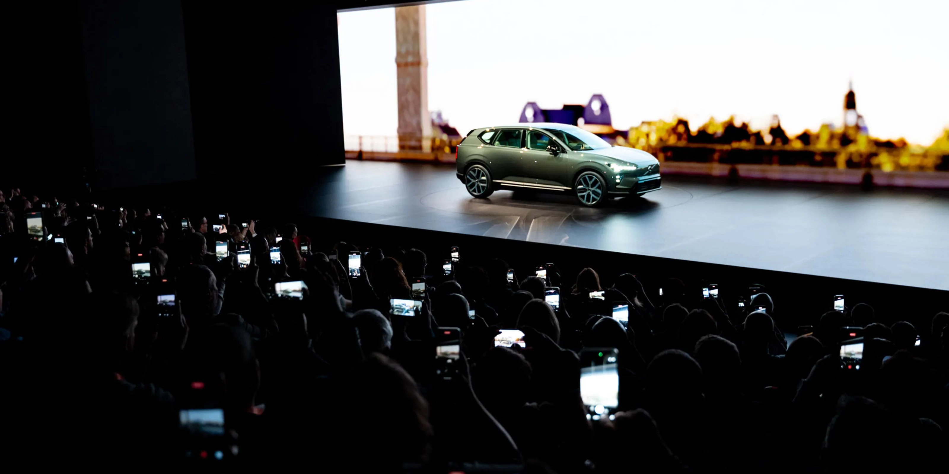 Elektrischer SUV wird auf einer Bühne präsentiert, das Publikum fotografiert mit Smartphones.