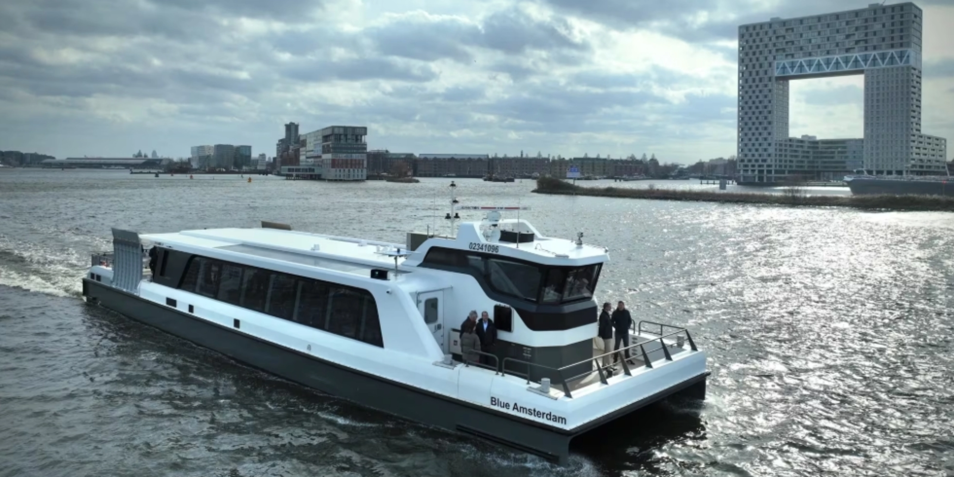 White passenger ferry on a river with modern city buildings in background