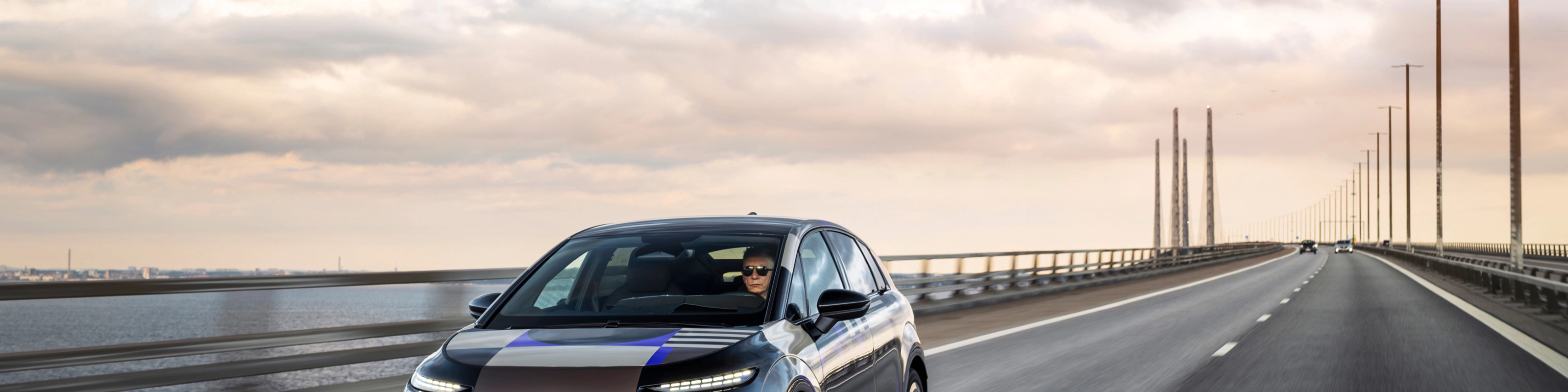 Audi prototype electric vehicle driving on an open road at sunset.