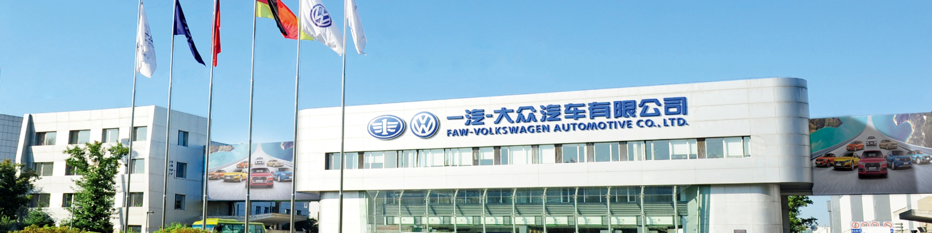 Haupteingang der FAW-Volkswagen Automotive Company mit Fahnen und Firmenschriftzug.