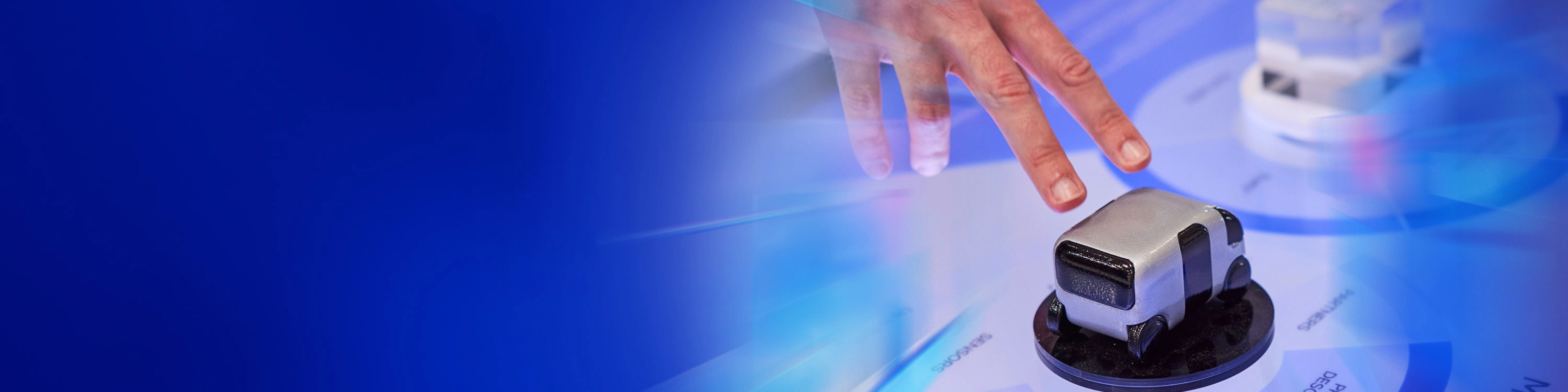 Eine Hand interagiert mit einem kleinen Fahrzeugmodell auf einer digitalen Fläche beim IAA Summit.