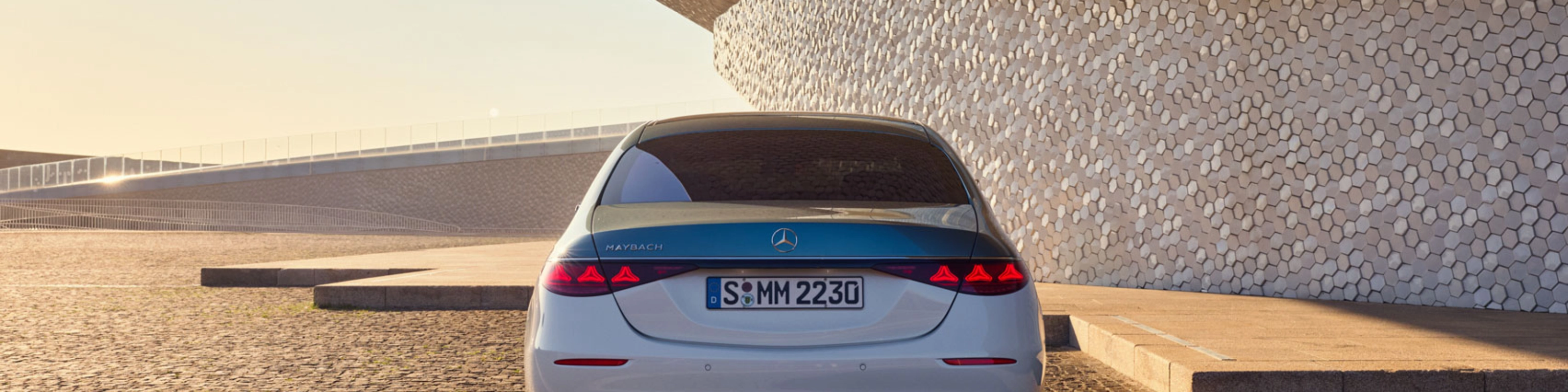 Rückansicht eines weißen Mercedes-Benz vor modernem Gebäude.