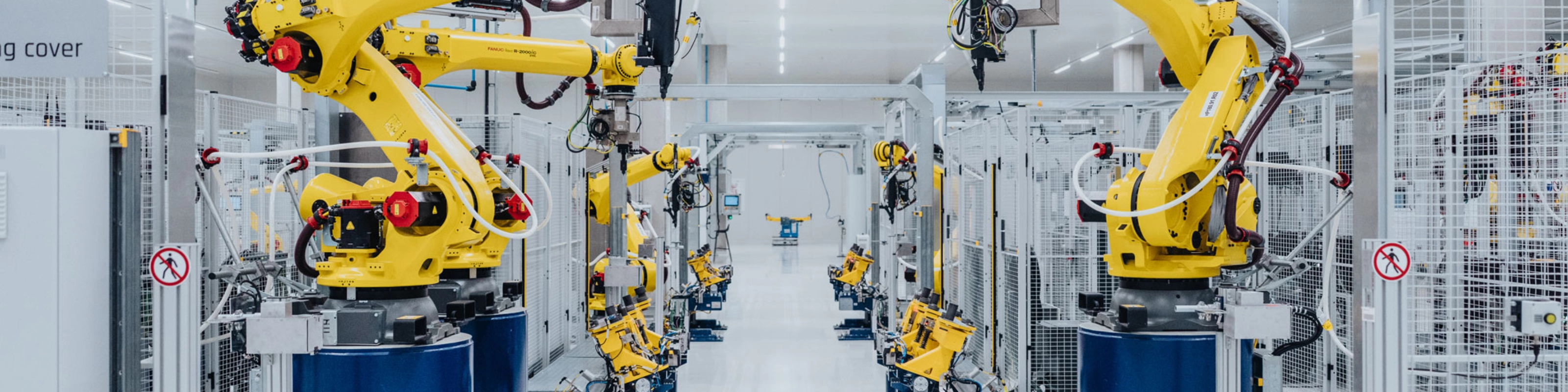 Automatisierte Fertigungslinie mit gelben Industrierobotern in einer Fabrikhalle.