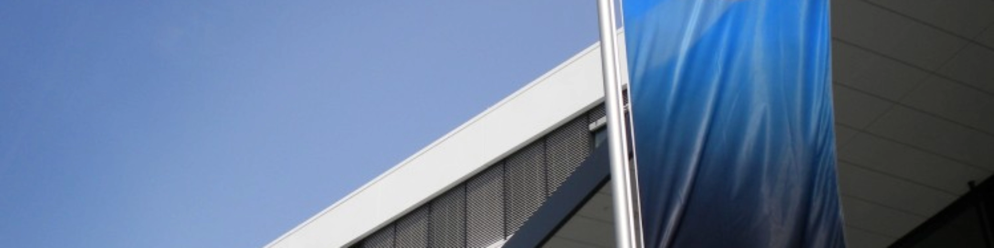Blaue ZF-Flagge vor einem modernen Bürogebäude mit weißer Fassade.
