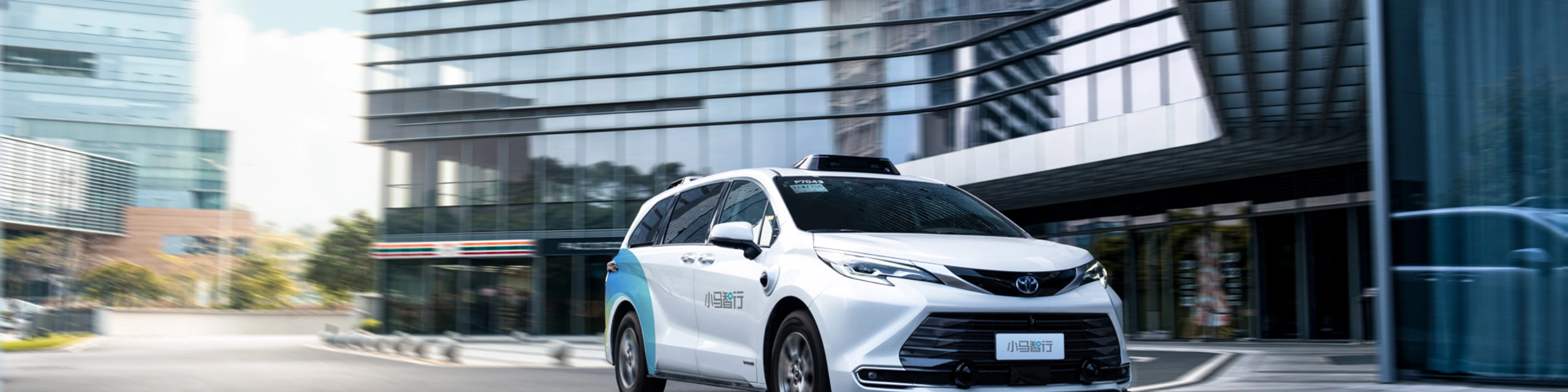 Autonomous minivan driving through modern city street.