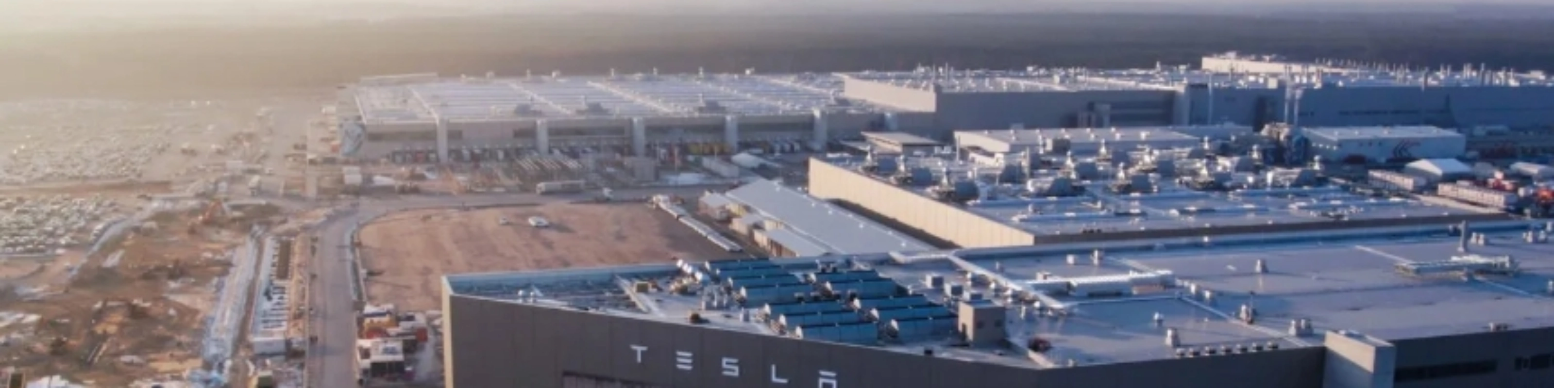 Luftaufnahme eines Tesla-Werks mit großen Produktionsgebäuden.