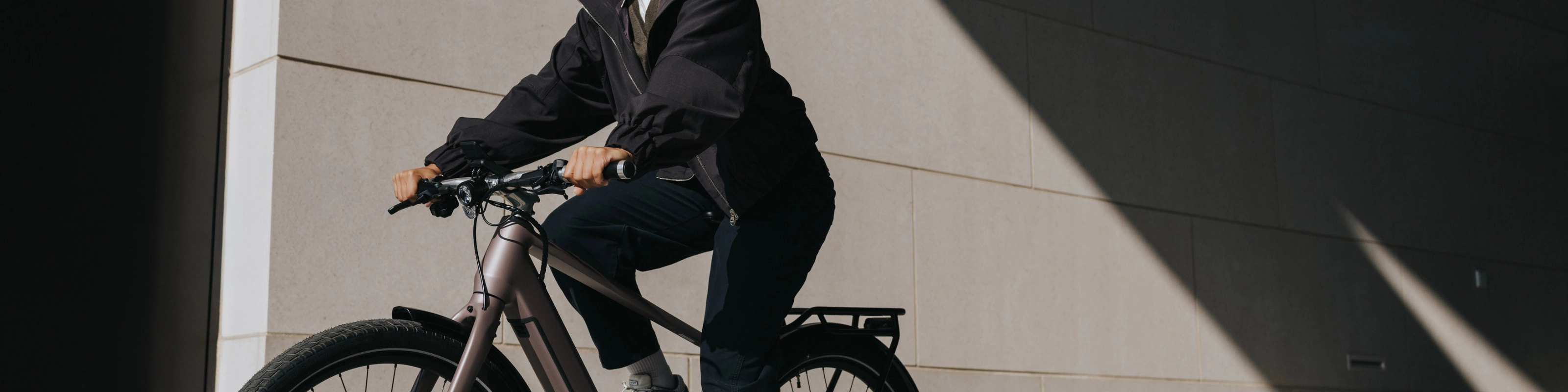 Person mit Helm fährt ein E-Bike neben einem modernen Gebäude.