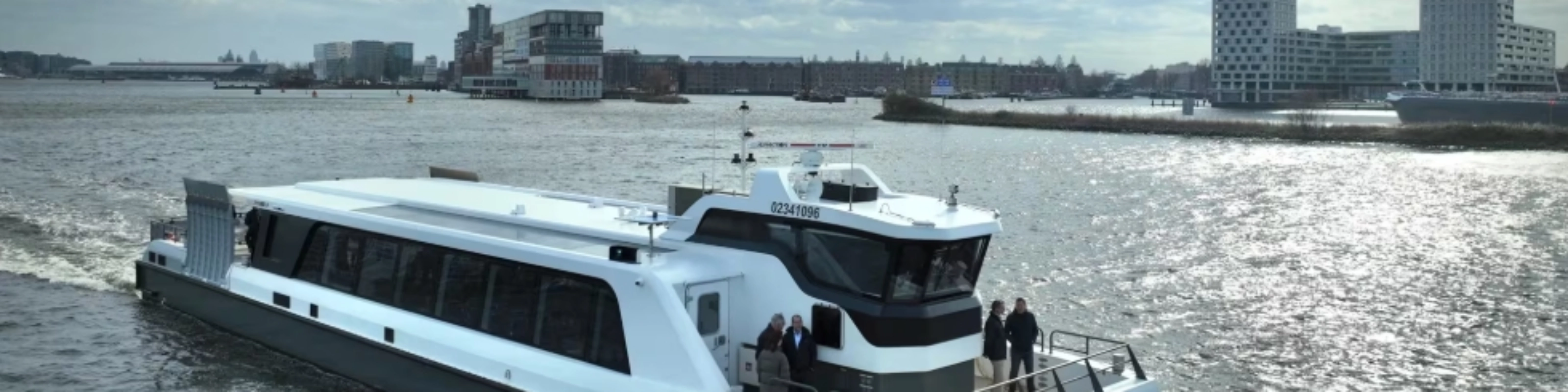 White passenger ferry on a river with modern city buildings in background