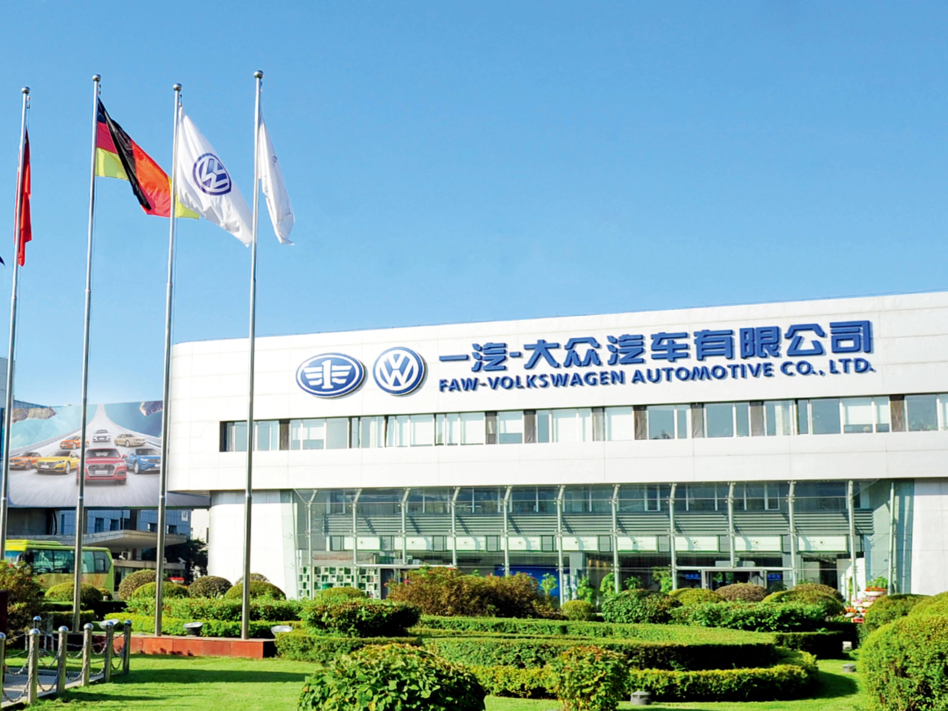 Haupteingang der FAW-Volkswagen Automotive Company mit Fahnen und Firmenschriftzug.