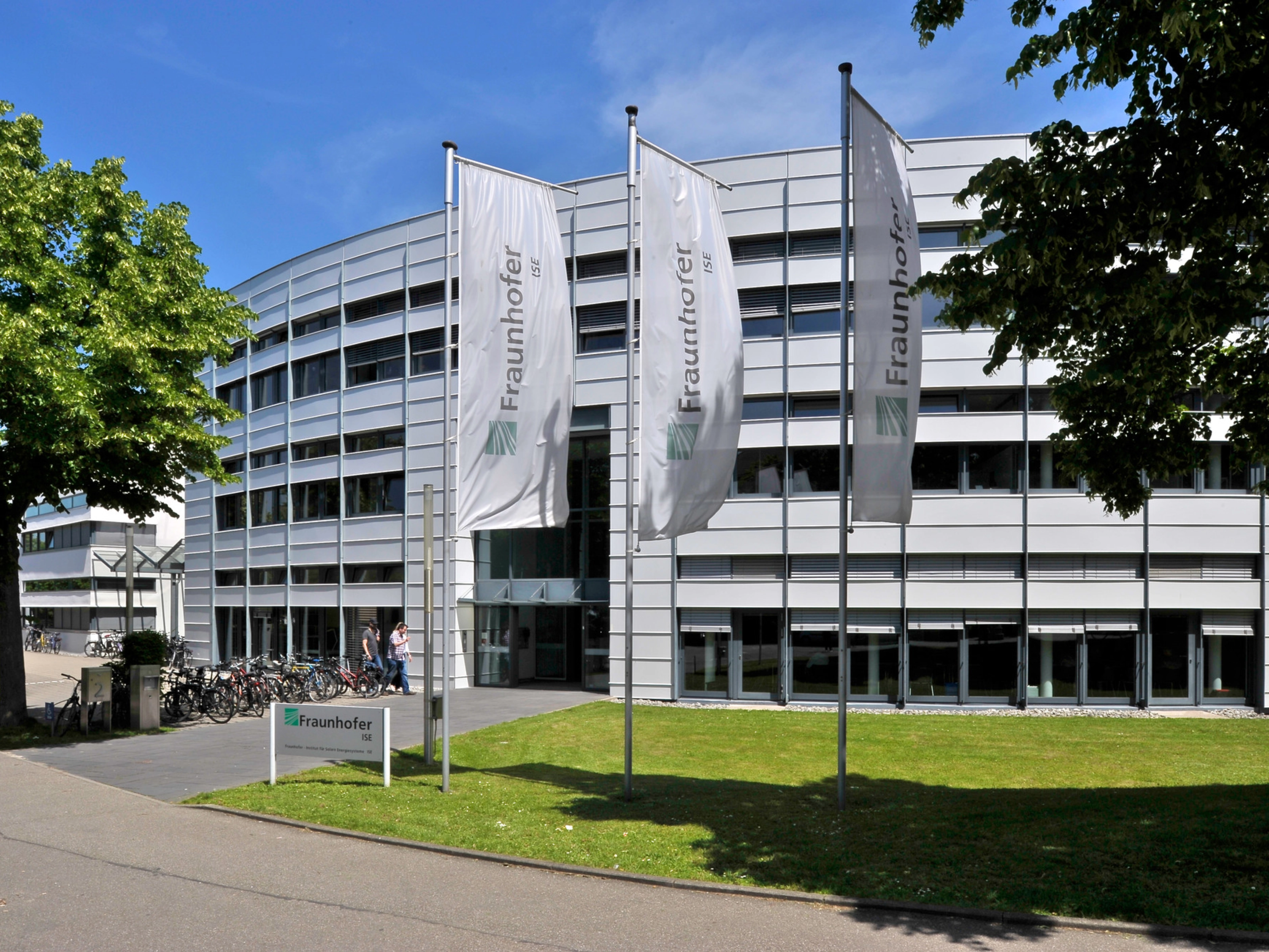 Modernes Fraunhofer-Institutsgebäude mit Fahnen und Bäumen davor.