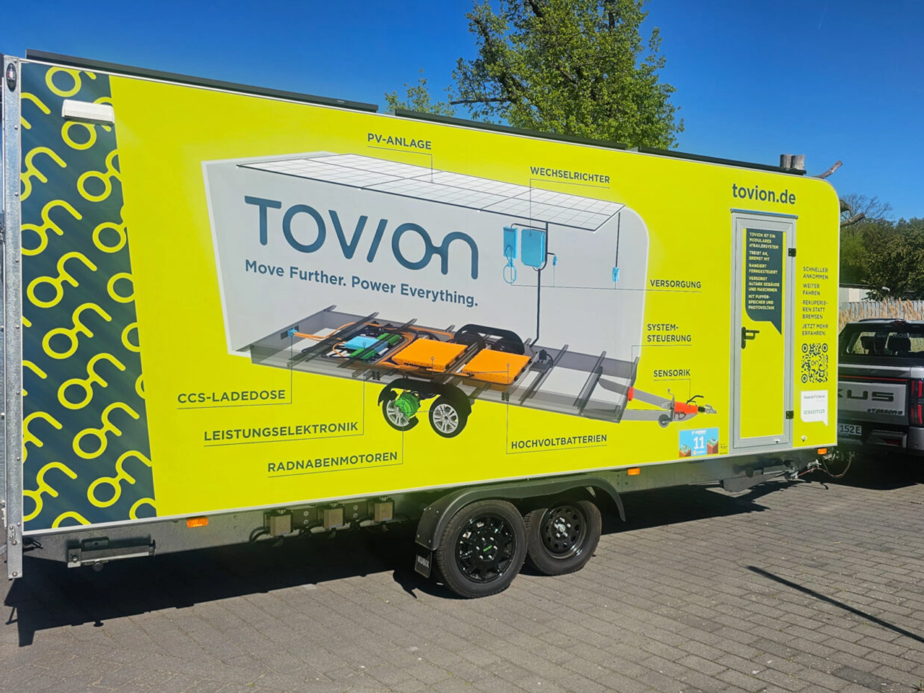 Yellow Tovion trailer with product graphic parked outdoors.