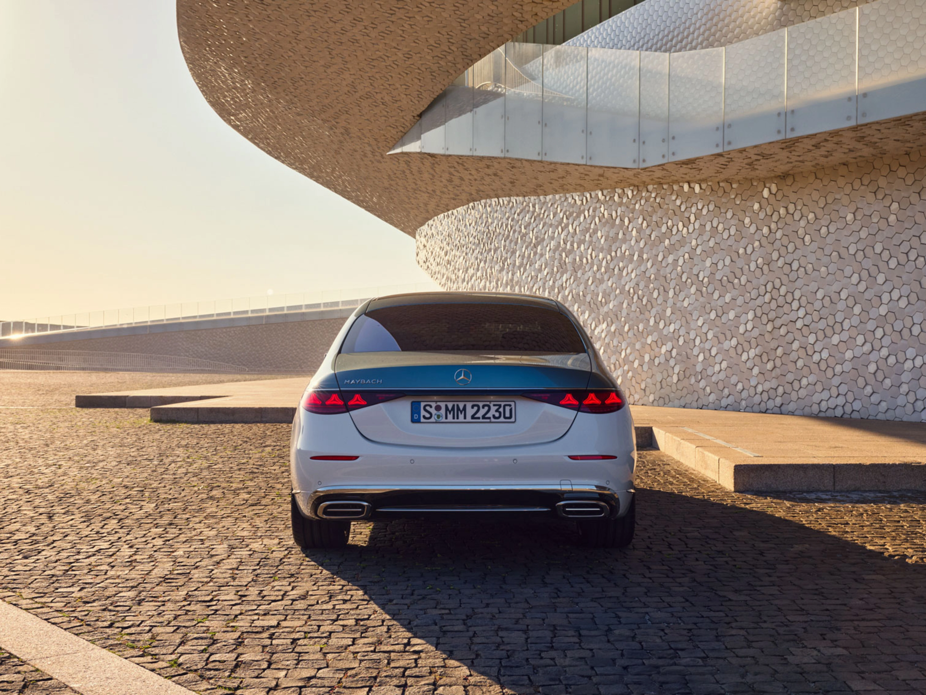 Rückansicht eines weißen Mercedes-Benz vor modernem Gebäude.