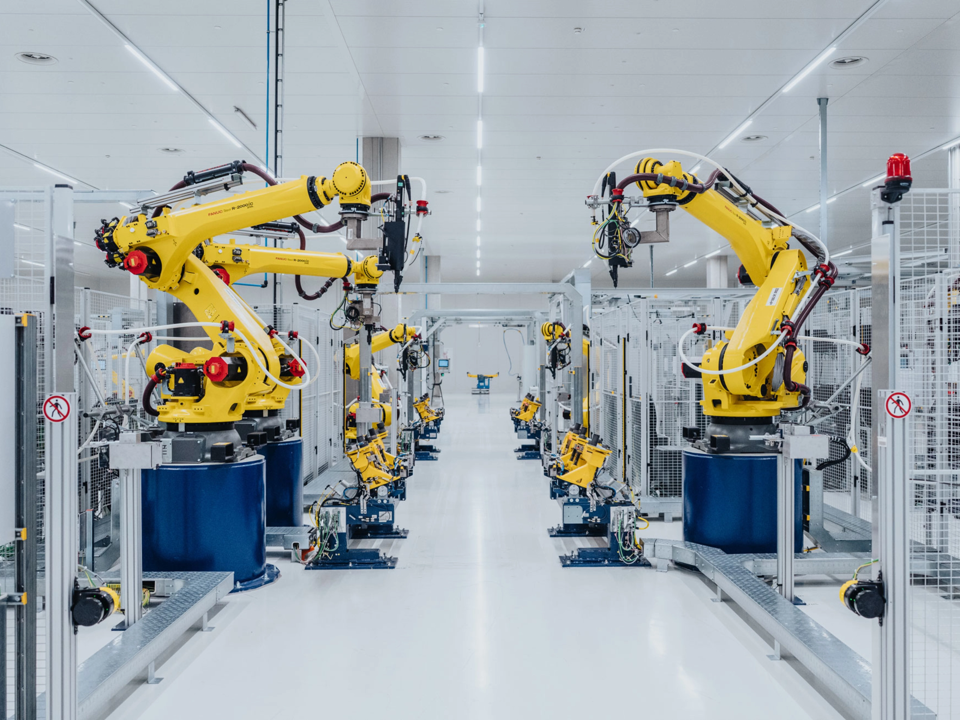 Automatisierte Fertigungslinie mit gelben Industrierobotern in einer Fabrikhalle.