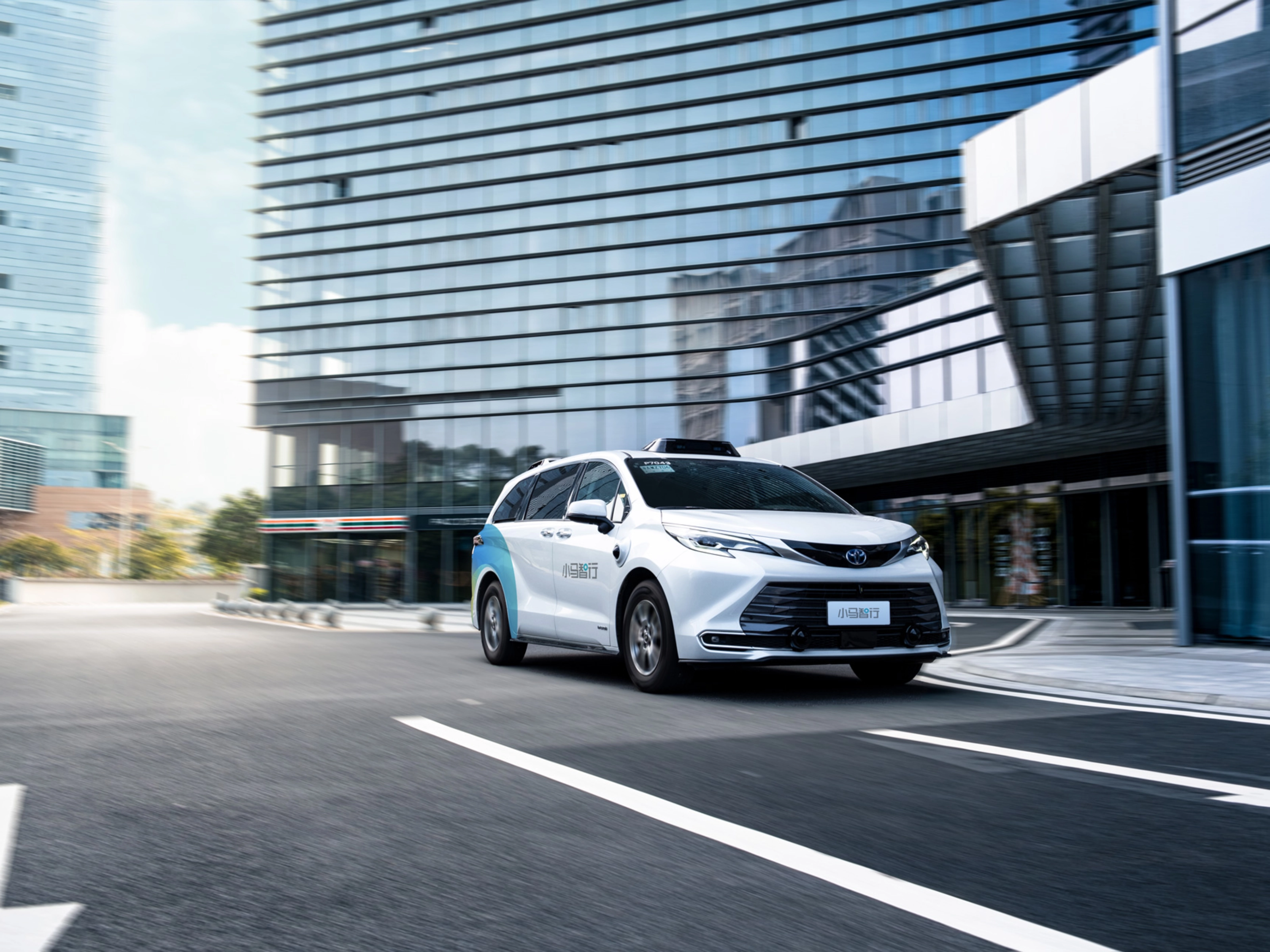 Autonomous minivan driving through modern city street.